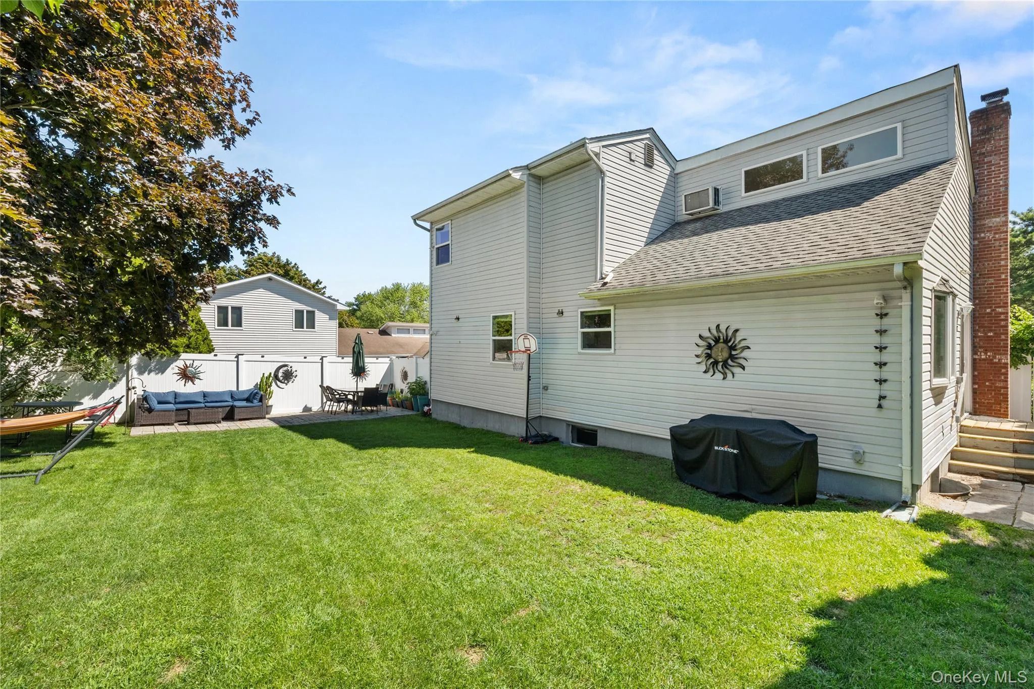 Expansive backyard featuring a manicured lawn, white privacy fencing, and a dedicated patio area Expansive backyard featuring a manicured lawn, white privacy fencing, and a dedicated patio area