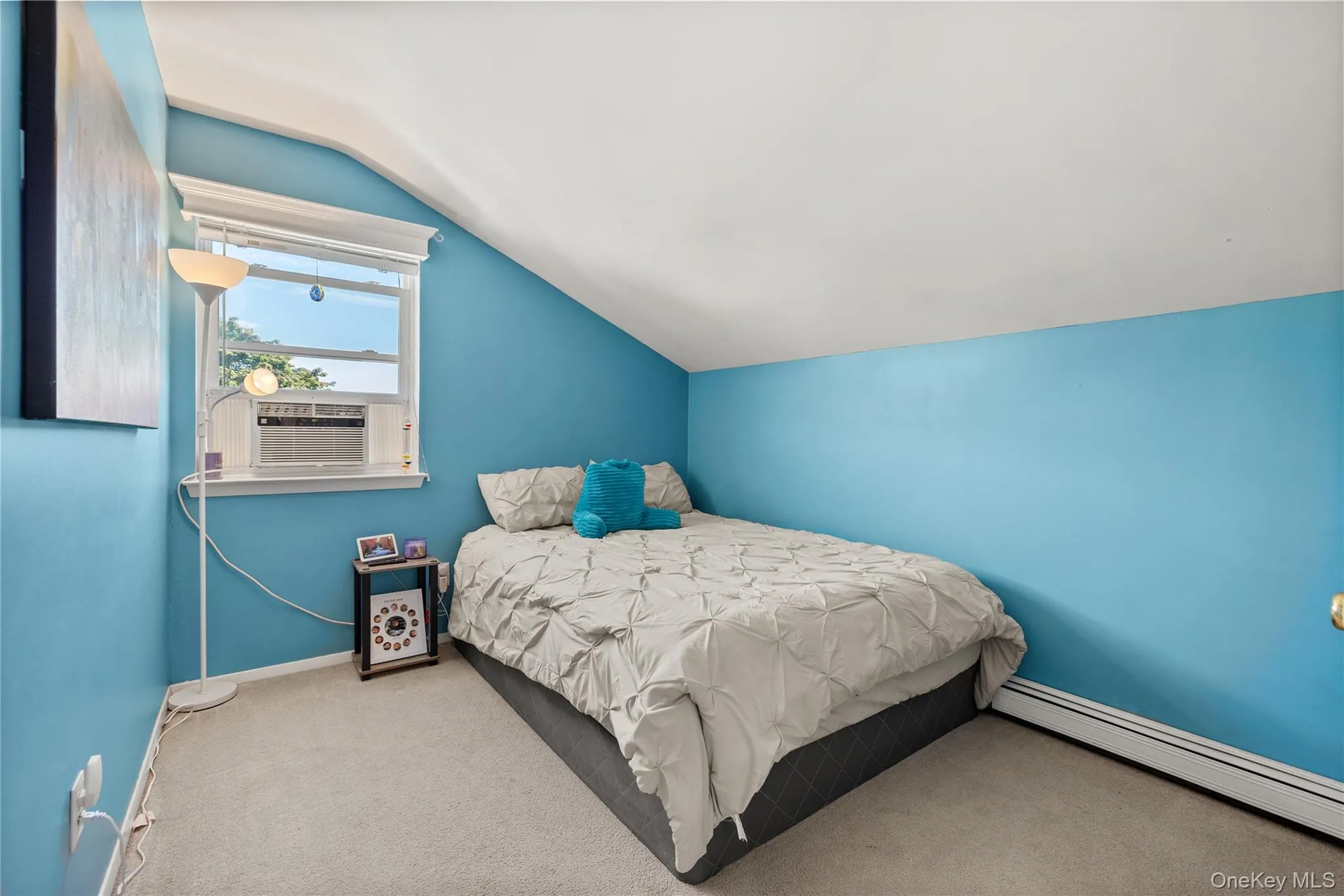 Carpeted room featuring a window with an air conditioning unit, sloped ceiling, and baseboard heating Carpeted room featuring a window with an air conditioning unit, sloped ceiling, and baseboard heating