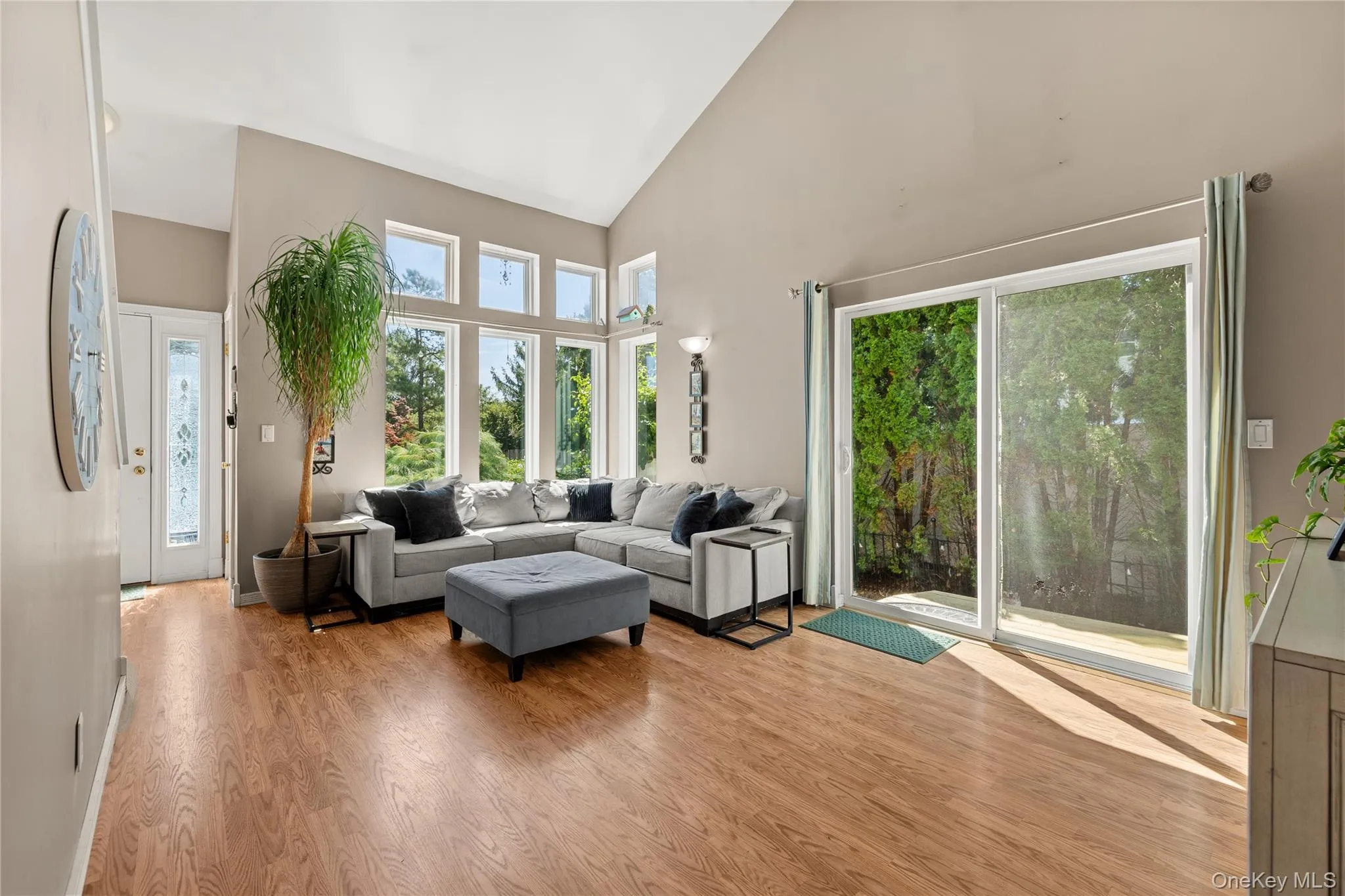 Vaulted ceiling with a wall of windows, wood-finish flooring, and a sliding glass door Vaulted ceiling with a wall of windows, wood-finish flooring, and a sliding glass door