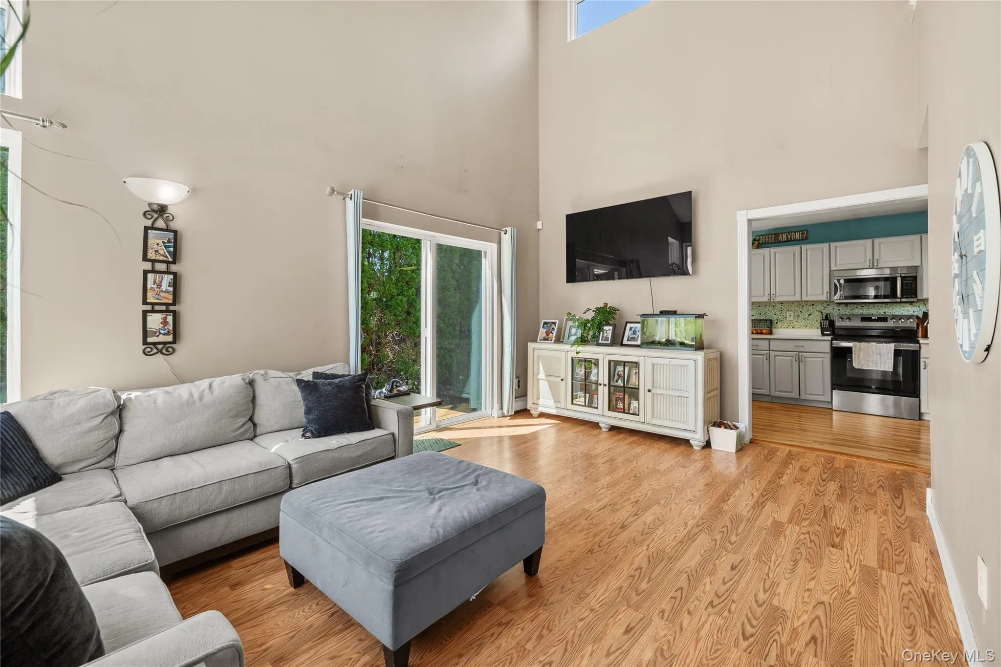 Open-concept living space featuring vaulted ceilings, abundant natural light from sliding glass doors, and wood-finish flooring throughout Open-concept living space featuring vaulted ceilings, abundant natural light from sliding glass doors, and wood-finish flooring throughout