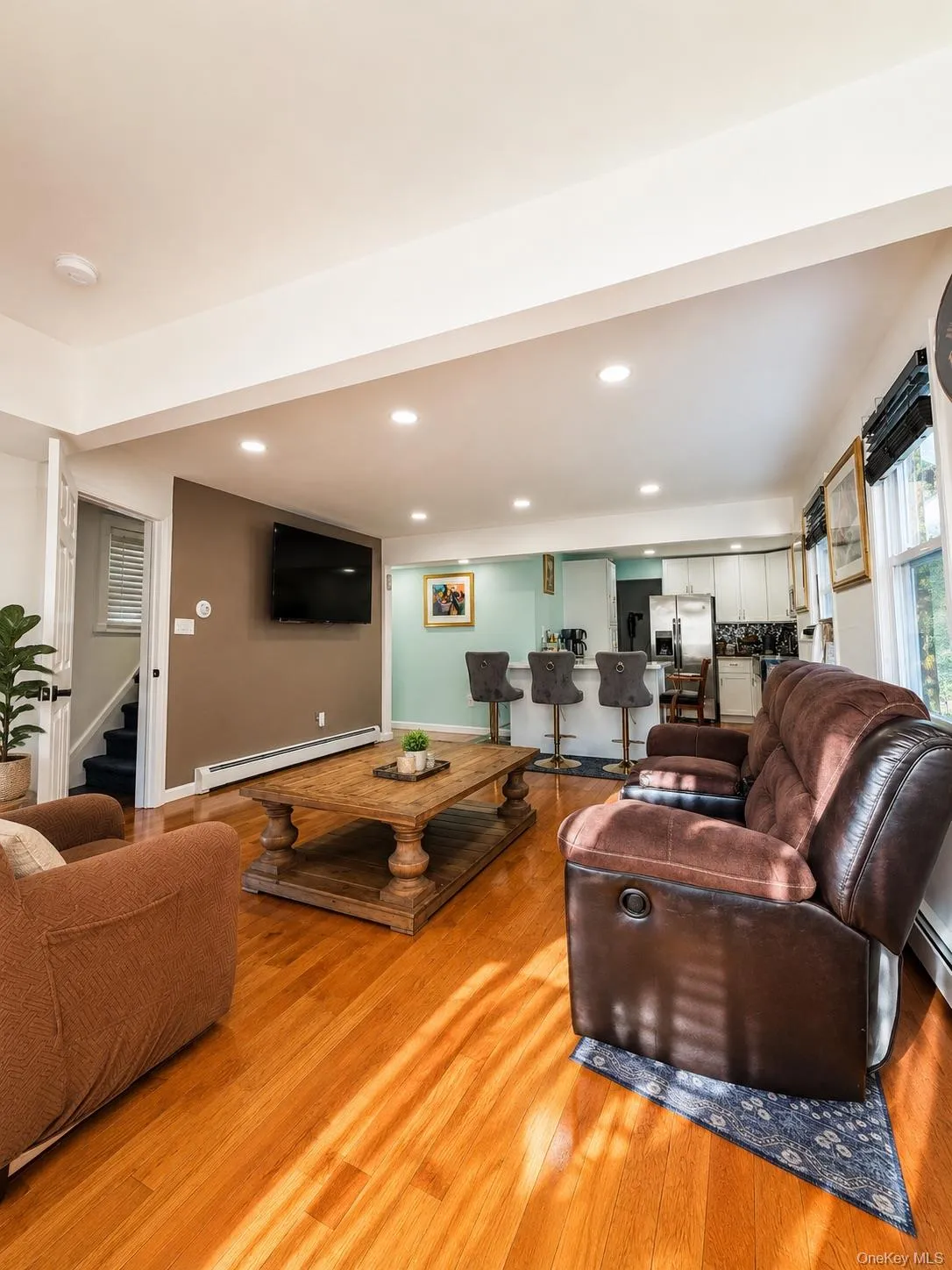 Spacious living area showcasing warm wood-finish flooring, recessed ceiling lighting, and a neutral color palette Spacious living area showcasing warm wood-finish flooring, recessed ceiling lighting, and a neutral color palette