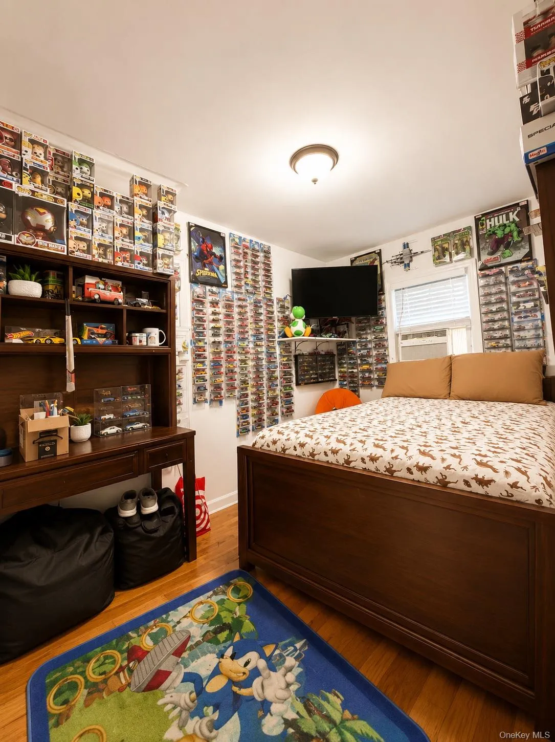Bedroom featuring wood-finish flooring, built-in shelving with display storage, wood-finish bed frame, and recessed ceiling lighting Bedroom featuring wood-finish flooring, built-in shelving with display storage, wood-finish bed frame, and recessed ceiling lighting