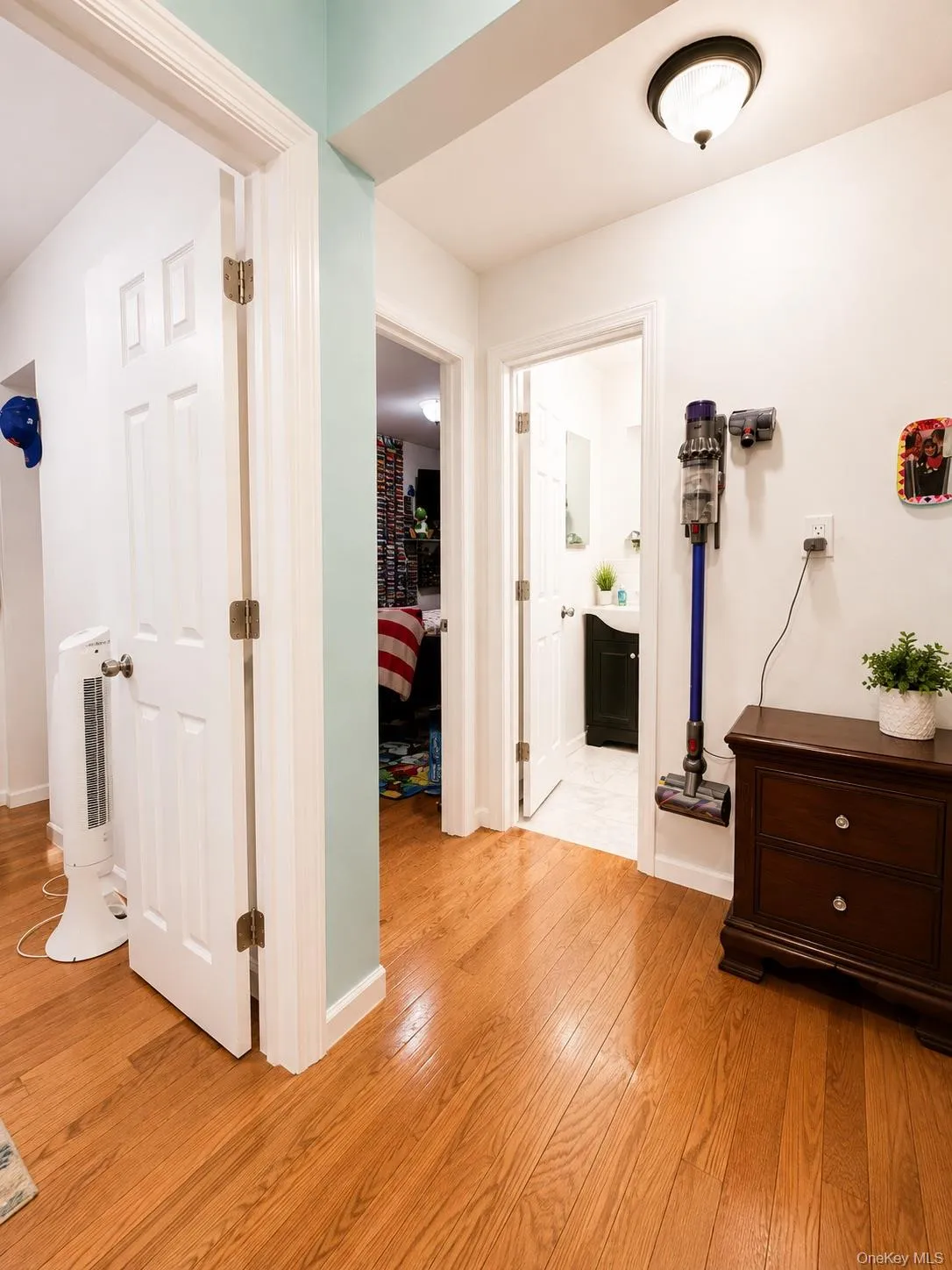 warm wood-finish flooring, white six-panel doors with brushed nickel hardware, soft overhead lighting, and fresh white walls warm wood-finish flooring, white six-panel doors with brushed nickel hardware, soft overhead lighting, and fresh white walls