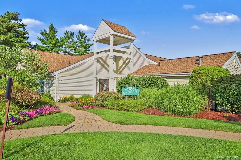 Clubhouse exterior featuring a prominent bell tower architectural element, neutral siding, and a brown shingle roof Clubhouse exterior featuring a prominent bell tower architectural element, neutral siding, and a brown shingle roof