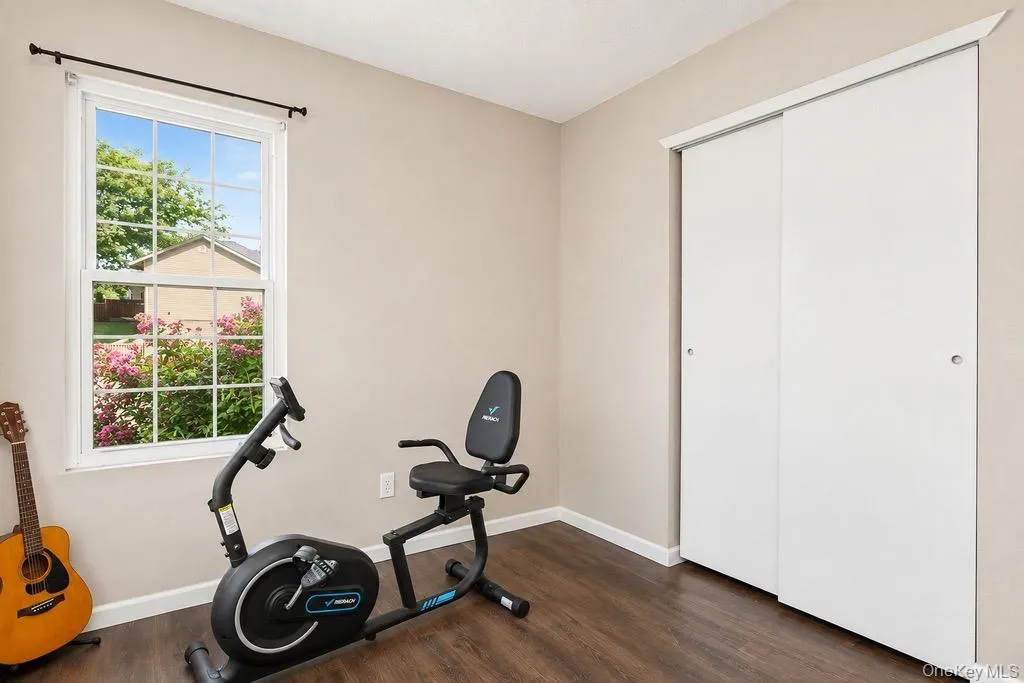 Interior room featuring wood-finish flooring, light neutral-toned walls, and a white framed window Interior room featuring wood-finish flooring, light neutral-toned walls, and a white framed window