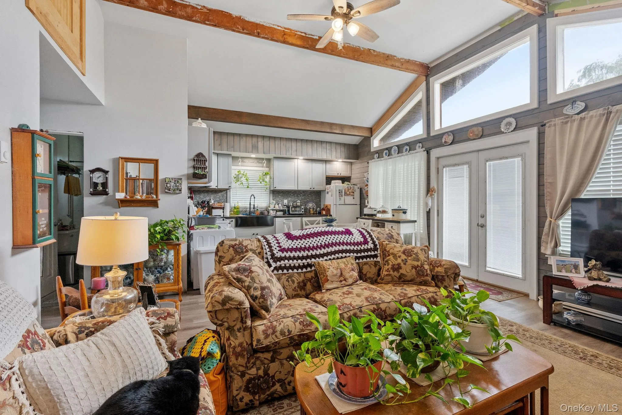 Living area featuring high vaulted ceiling, beamed ceiling, a ceiling fan, light wood finished floors, and french doors Living area featuring high vaulted ceiling, beamed ceiling, a ceiling fan, light wood finished floors, and french doors