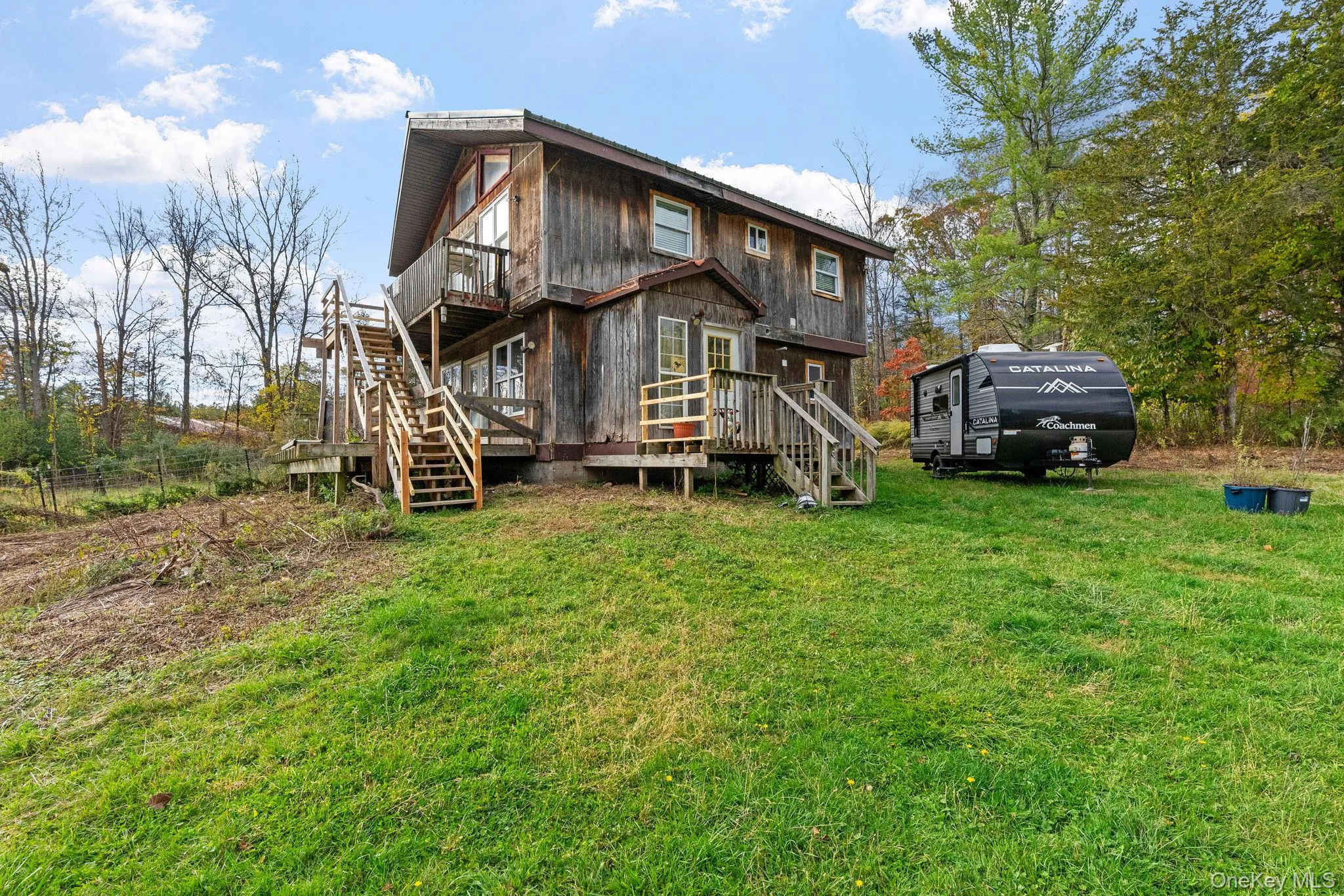 Back of house with stairs, a wooden deck, and a lawn Back of house with stairs, a wooden deck, and a lawn