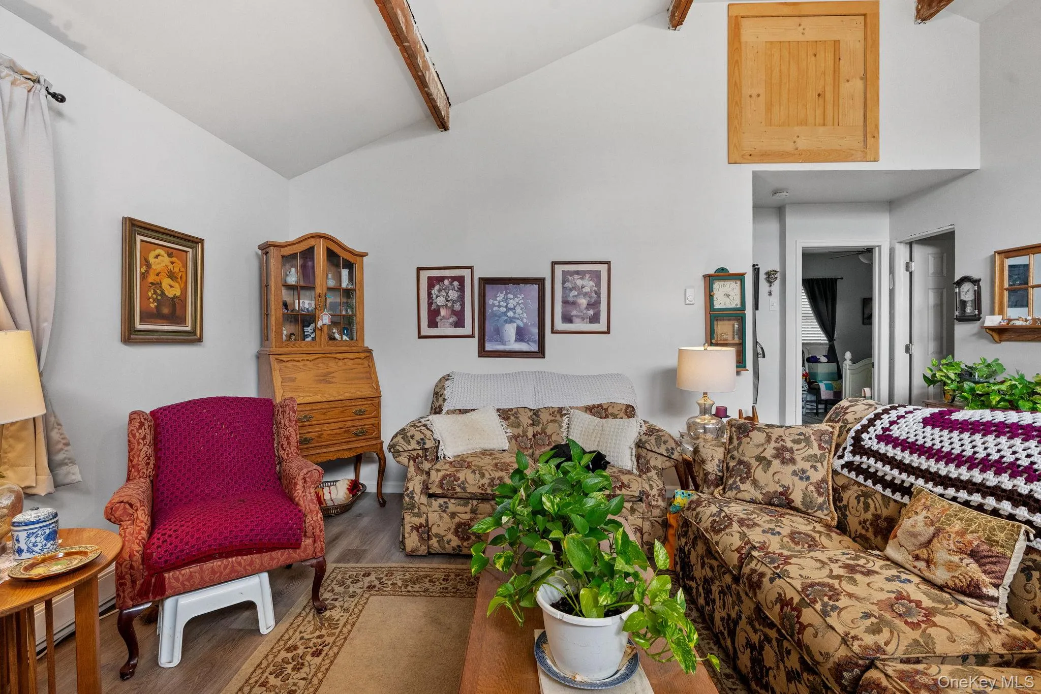 Living area featuring beamed ceiling, wood finished floors, and high vaulted ceiling Living area featuring beamed ceiling, wood finished floors, and high vaulted ceiling