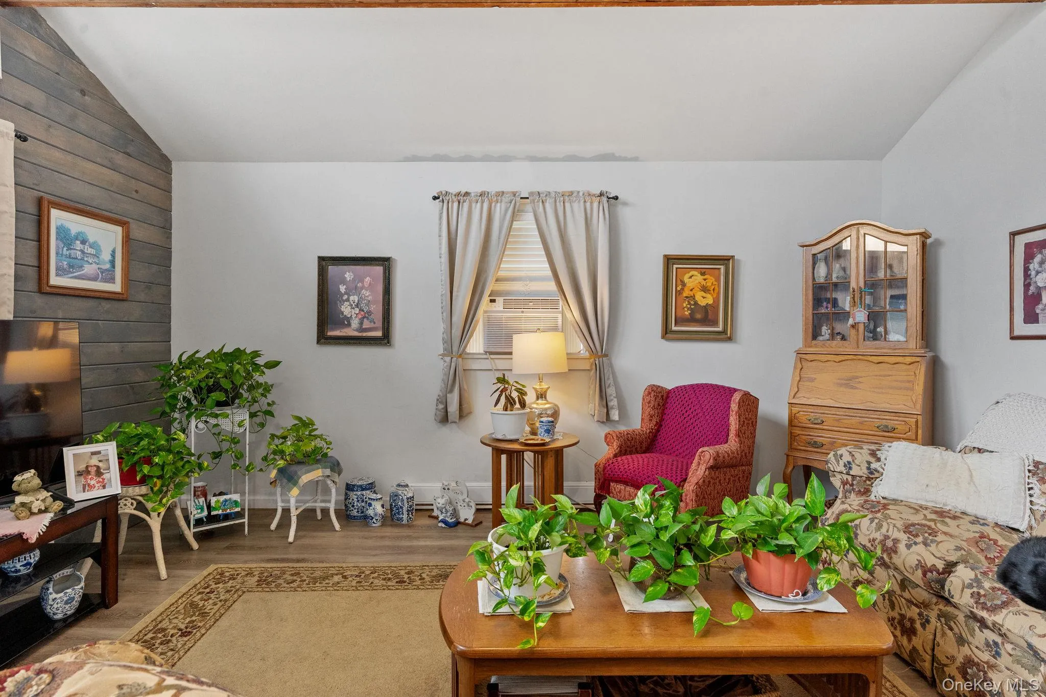 Living area featuring wood finished floors, vaulted ceiling, and wood walls Living area featuring wood finished floors, vaulted ceiling, and wood walls