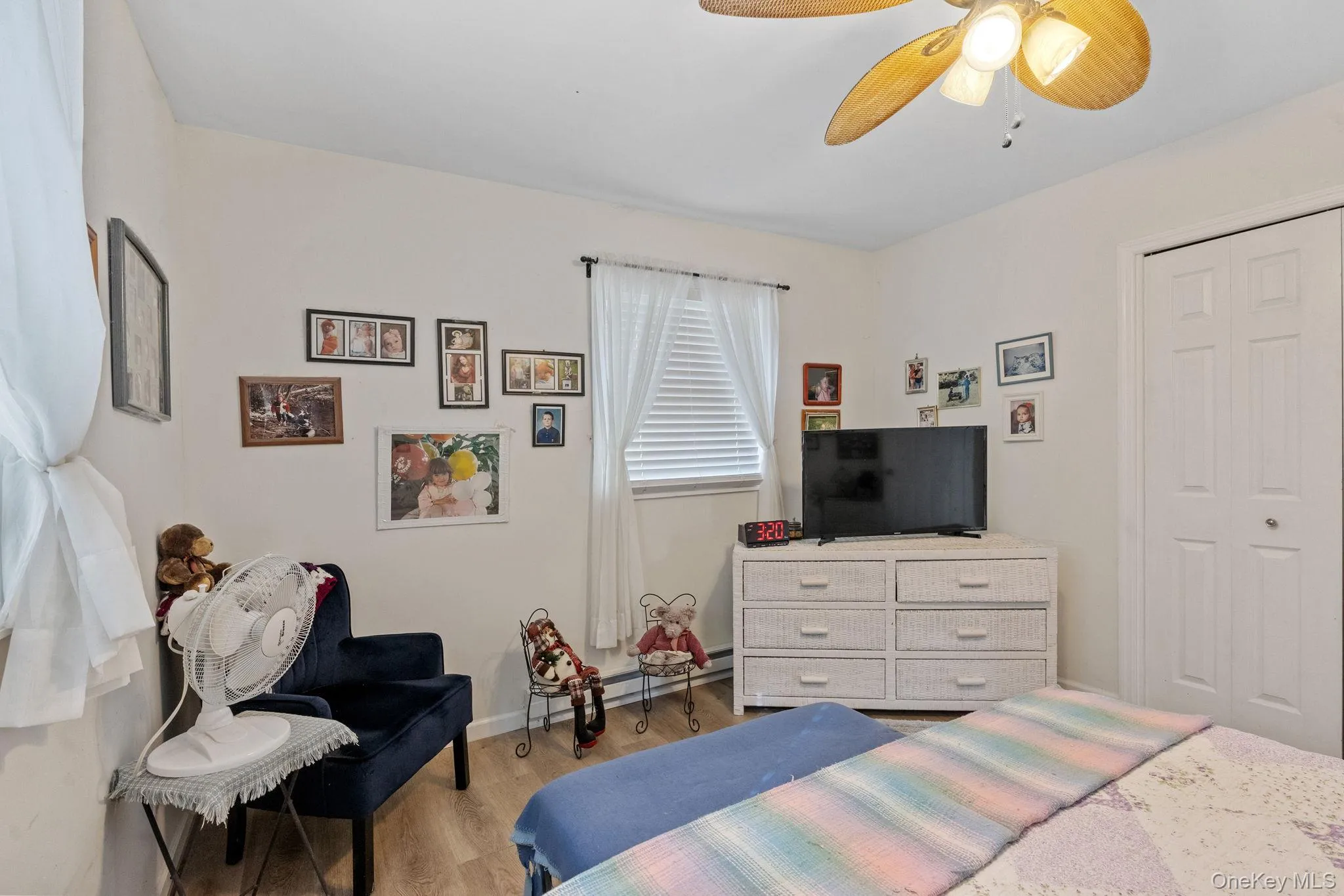 Bedroom featuring wood finished floors, ceiling fan, a closet, and a baseboard radiator Bedroom featuring wood finished floors, ceiling fan, a closet, and a baseboard radiator
