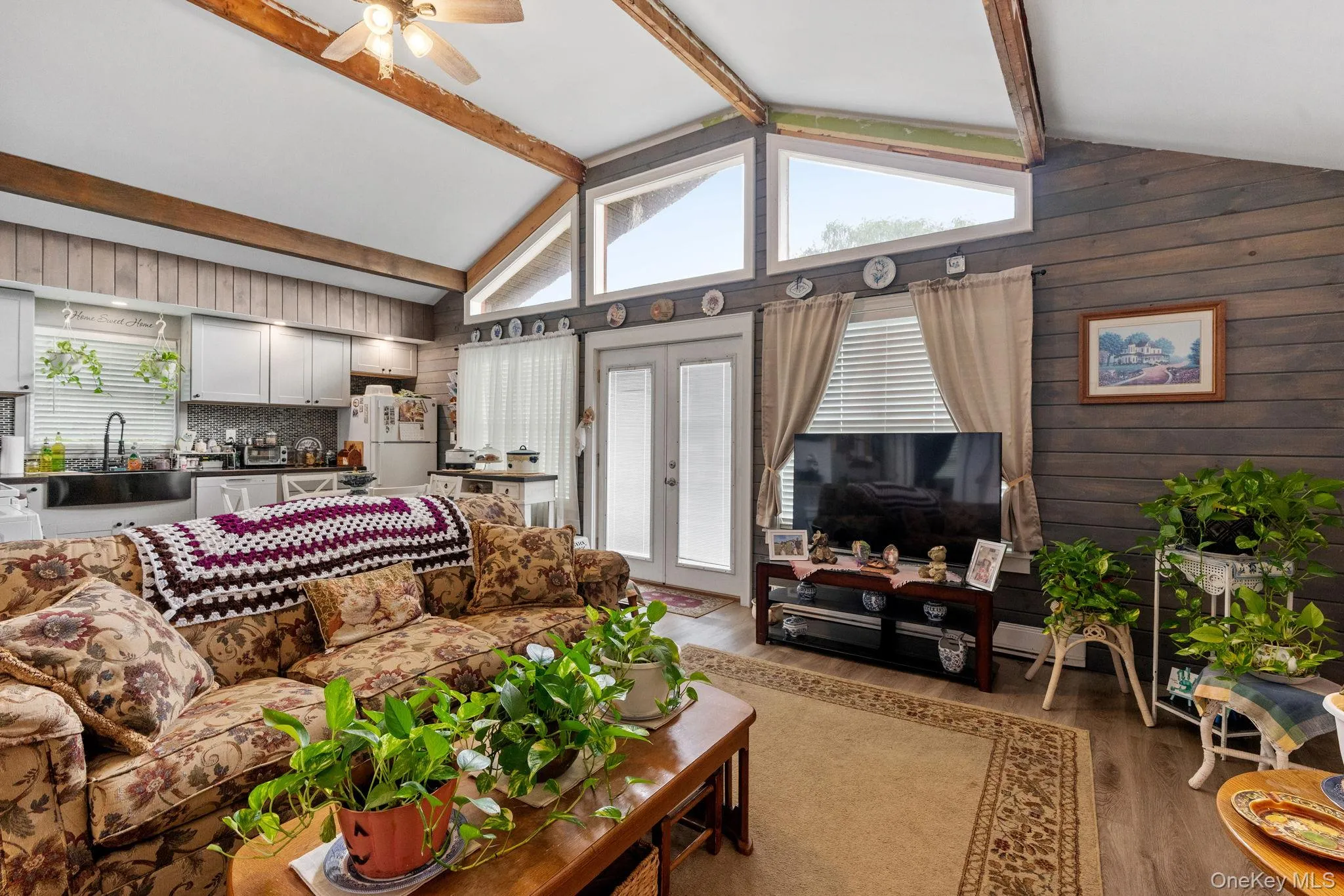 Living room with light wood-type flooring, beamed ceiling, ceiling fan, and high vaulted ceiling Living room with light wood-type flooring, beamed ceiling, ceiling fan, and high vaulted ceiling