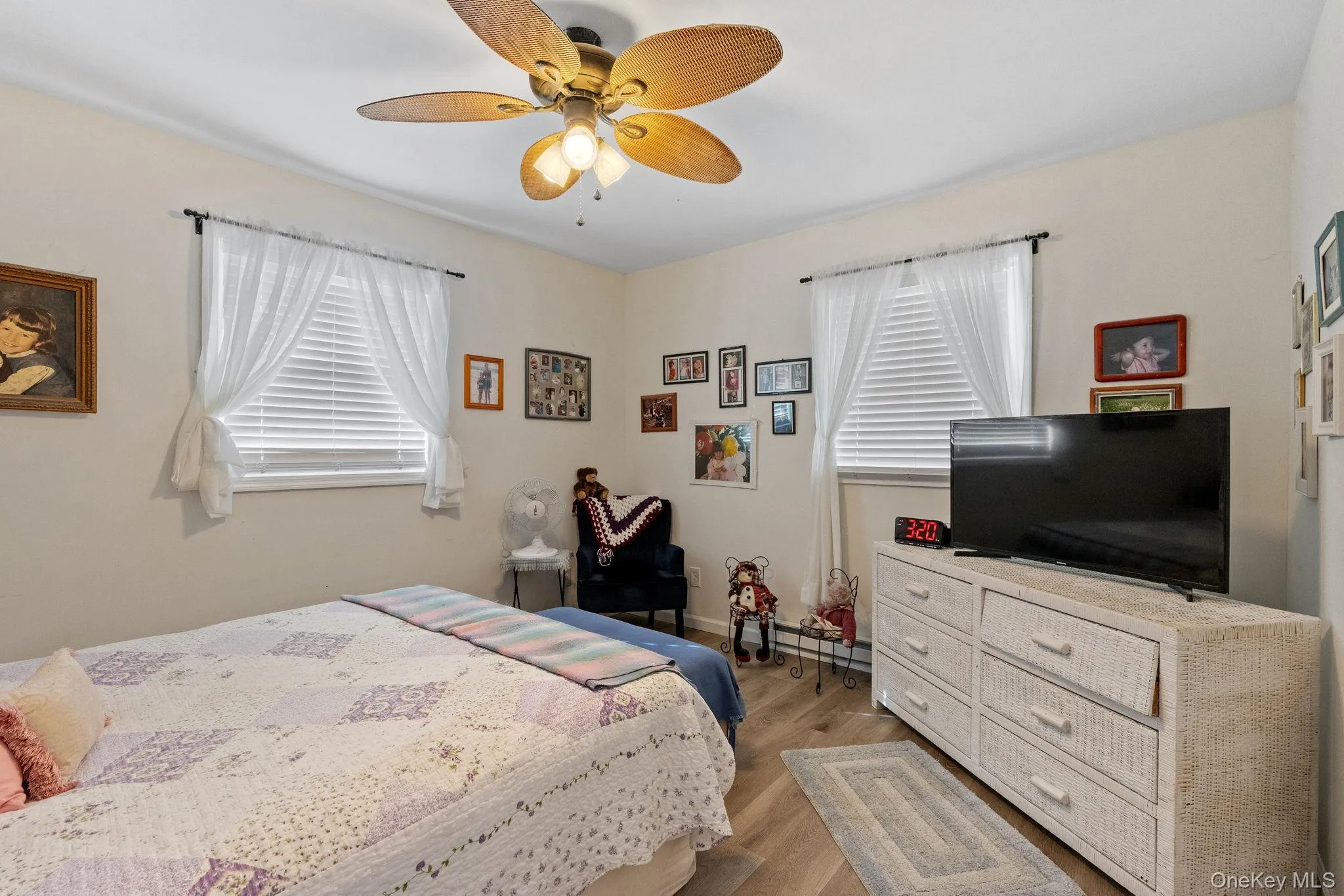 Bedroom featuring light wood-style flooring, multiple windows, a ceiling fan, and a baseboard radiator Bedroom featuring light wood-style flooring, multiple windows, a ceiling fan, and a baseboard radiator