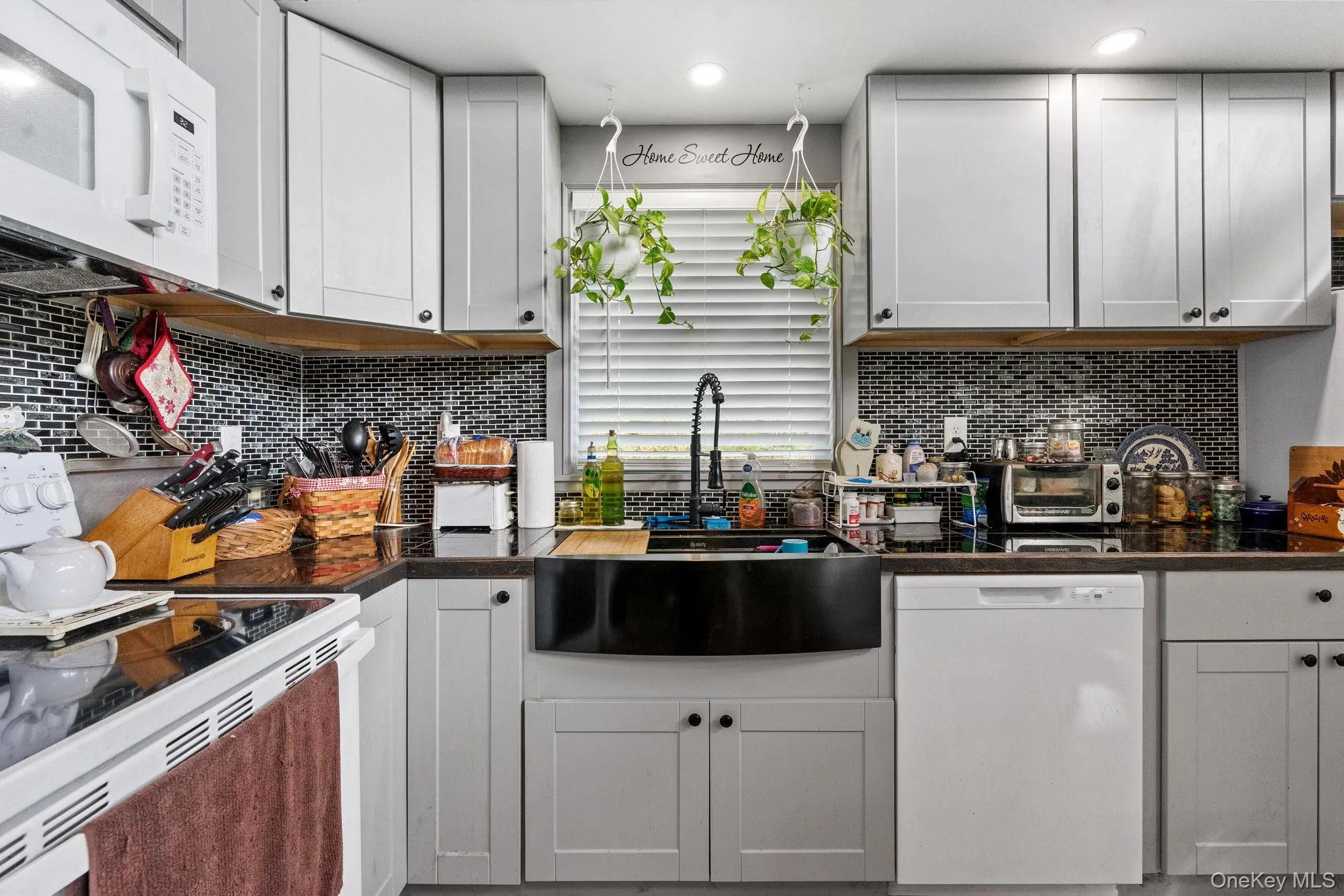 Kitchen with white appliances, decorative backsplash, and white cabinets Kitchen with white appliances, decorative backsplash, and white cabinets