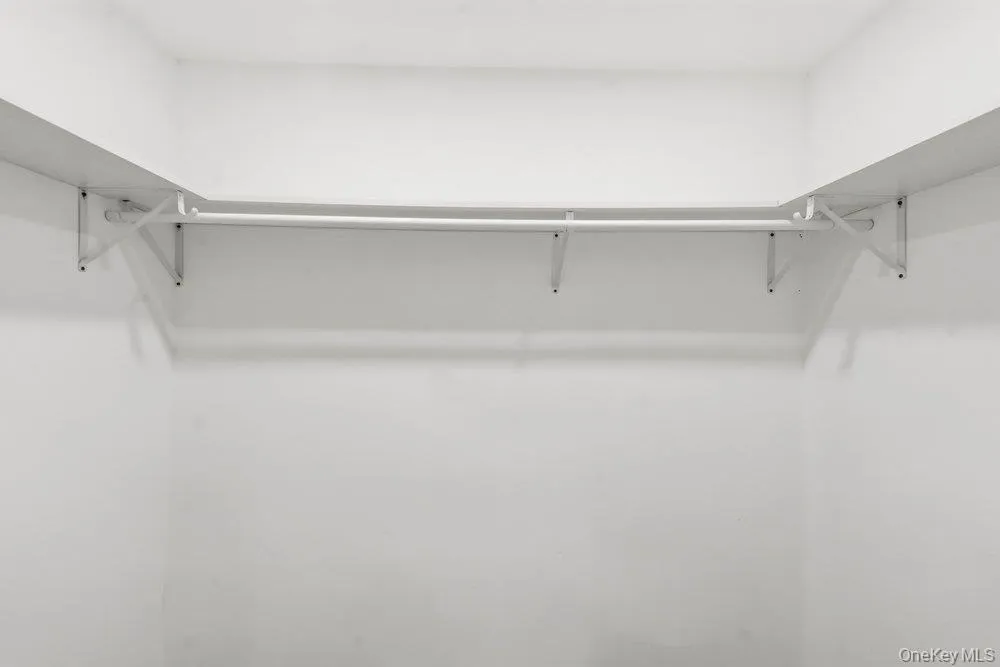 Primary Bedroom Has a Walk-in Closet with a U-shaped closet system featuring white shelving Clothes Rod providing ample storage space Primary Bedroom Has a Walk-in Closet with a U-shaped closet system featuring white shelving Clothes Rod providing ample storage space