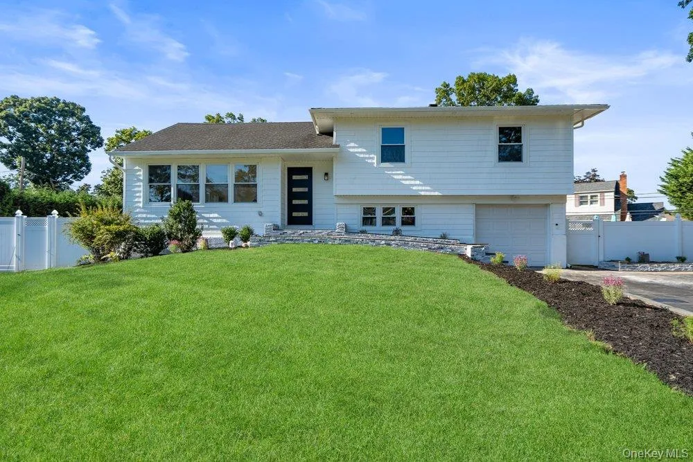 Split Level Home Featuring Large Front Yard, attached Garage, Dark Entry Door with vertical glass inserts, and Pretty White Perimeter fence Split Level Home Featuring Large Front Yard, attached Garage, Dark Entry Door with vertical glass inserts, and Pretty White Perimeter fence