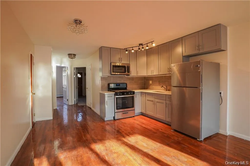 Open-concept kitchen featuring gray cabinetry, stainless steel appliances, and a tiled backsplash Open-concept kitchen featuring gray cabinetry, stainless steel appliances, and a tiled backsplash