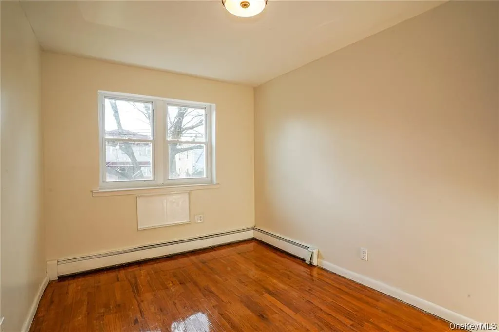 Room featuring wood-finish flooring, neutral wall paint, and a double window Room featuring wood-finish flooring, neutral wall paint, and a double window