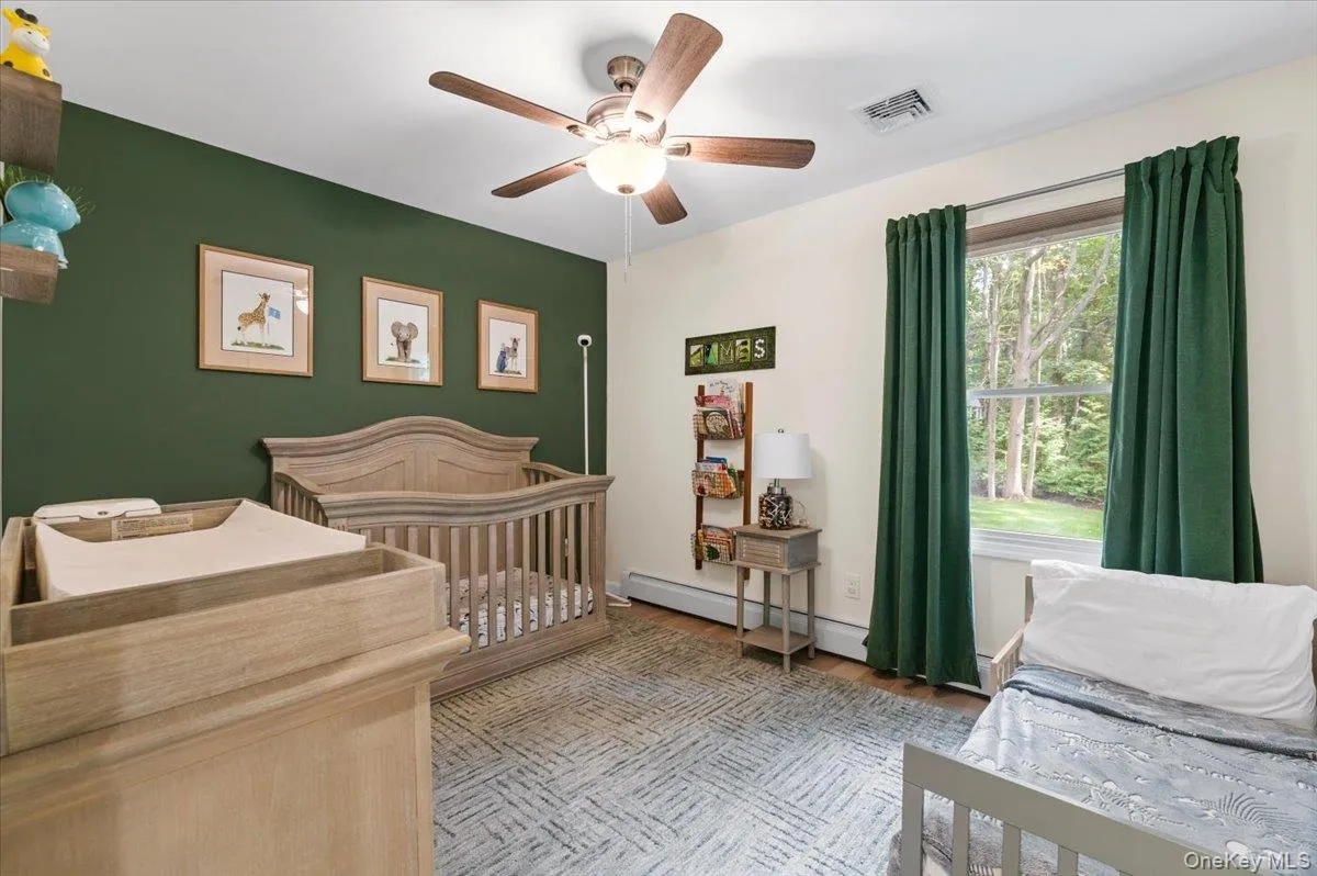Room with a painted accent wall, a window offering exterior tree views, and a ceiling fan with light fixture Room with a painted accent wall, a window offering exterior tree views, and a ceiling fan with light fixture