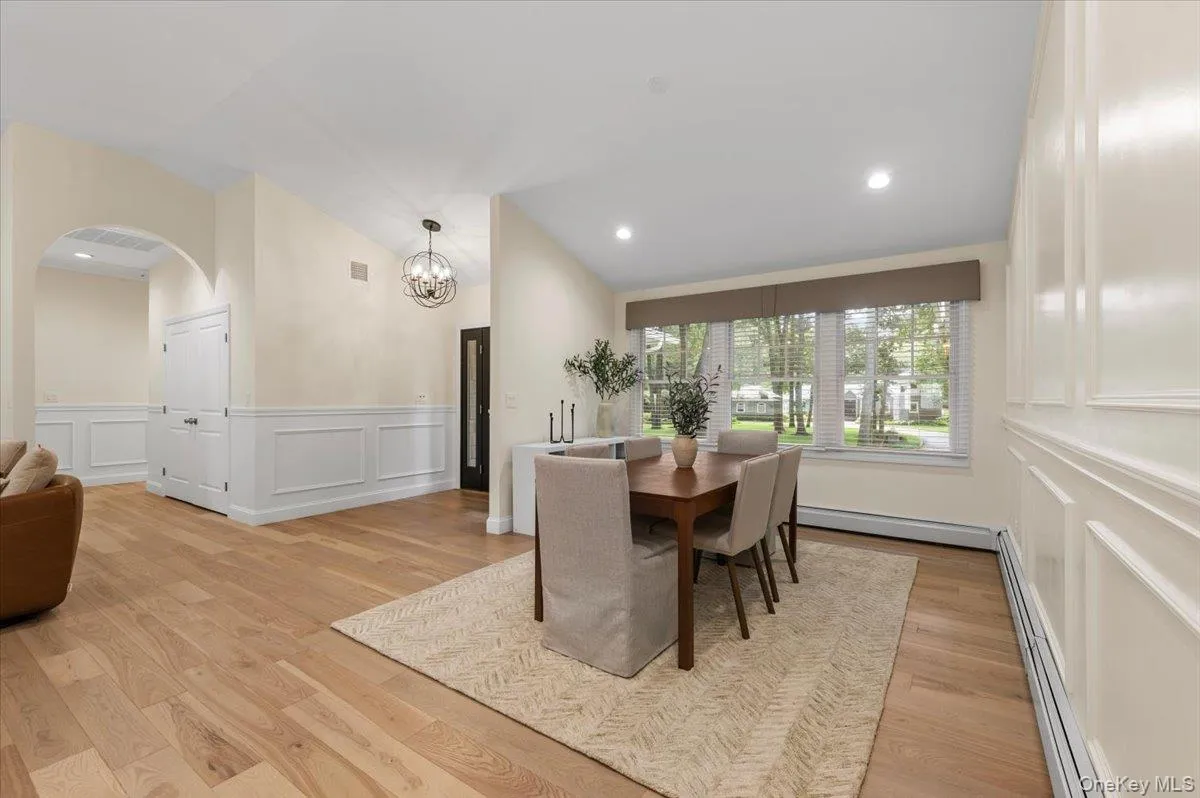 Vaulted ceiling with recessed lighting, wood-finish flooring, wainscoting, arched doorway, and a decorative orb chandelier Vaulted ceiling with recessed lighting, wood-finish flooring, wainscoting, arched doorway, and a decorative orb chandelier