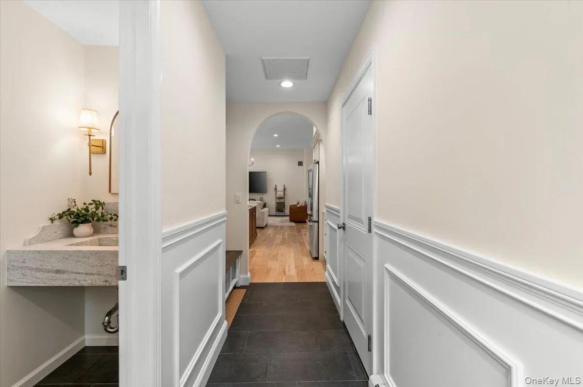 Hallway featuring wainscoting, dark-toned flooring, and an arched doorway Hallway featuring wainscoting, dark-toned flooring, and an arched doorway