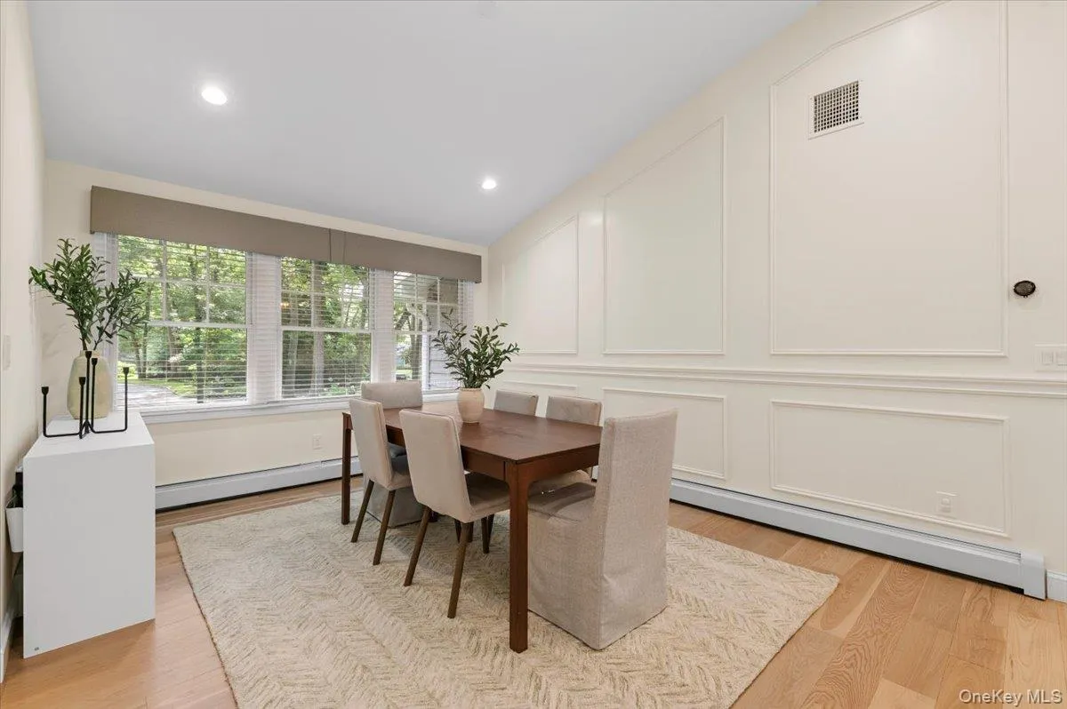 Vaulted ceiling with recessed lighting, wood-finish flooring, paneled wall detailing, and multiple windows with blinds Vaulted ceiling with recessed lighting, wood-finish flooring, paneled wall detailing, and multiple windows with blinds