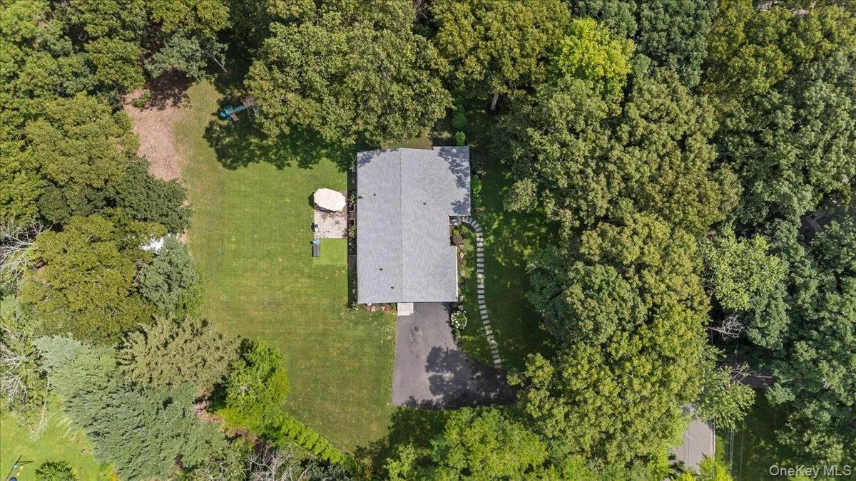 Expansive property with a shingle roof, mature perimeter trees, and a paved driveway Expansive property with a shingle roof, mature perimeter trees, and a paved driveway