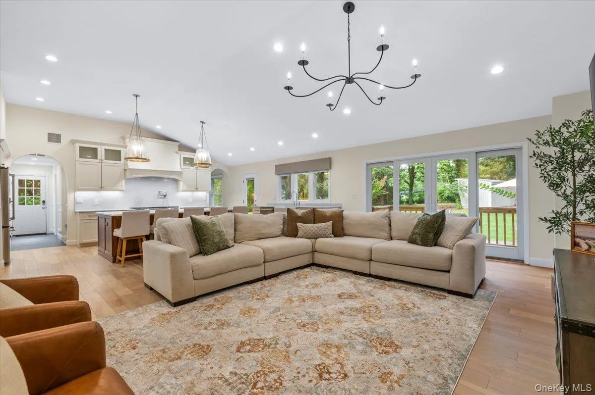 Expansive living area with vaulted ceilings, recessed lighting, hardwood flooring, and a large sliding glass door Expansive living area with vaulted ceilings, recessed lighting, hardwood flooring, and a large sliding glass door