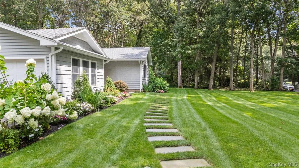 Expansive lawn featuring a stepping stone pathway, mature trees, and landscaped garden beds Expansive lawn featuring a stepping stone pathway, mature trees, and landscaped garden beds