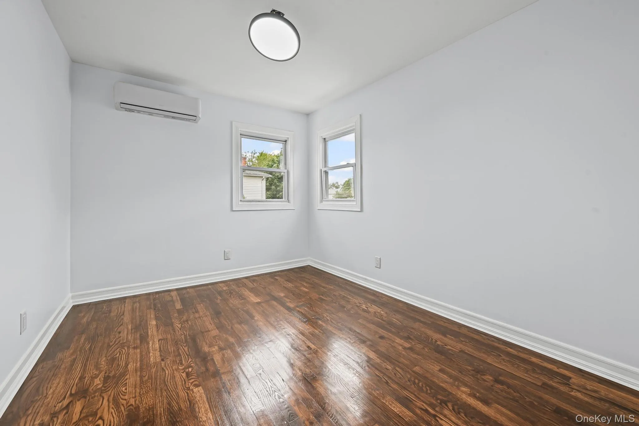 Spare room with dark wood finished floors and an AC wall unit Spare room with dark wood finished floors and an AC wall unit