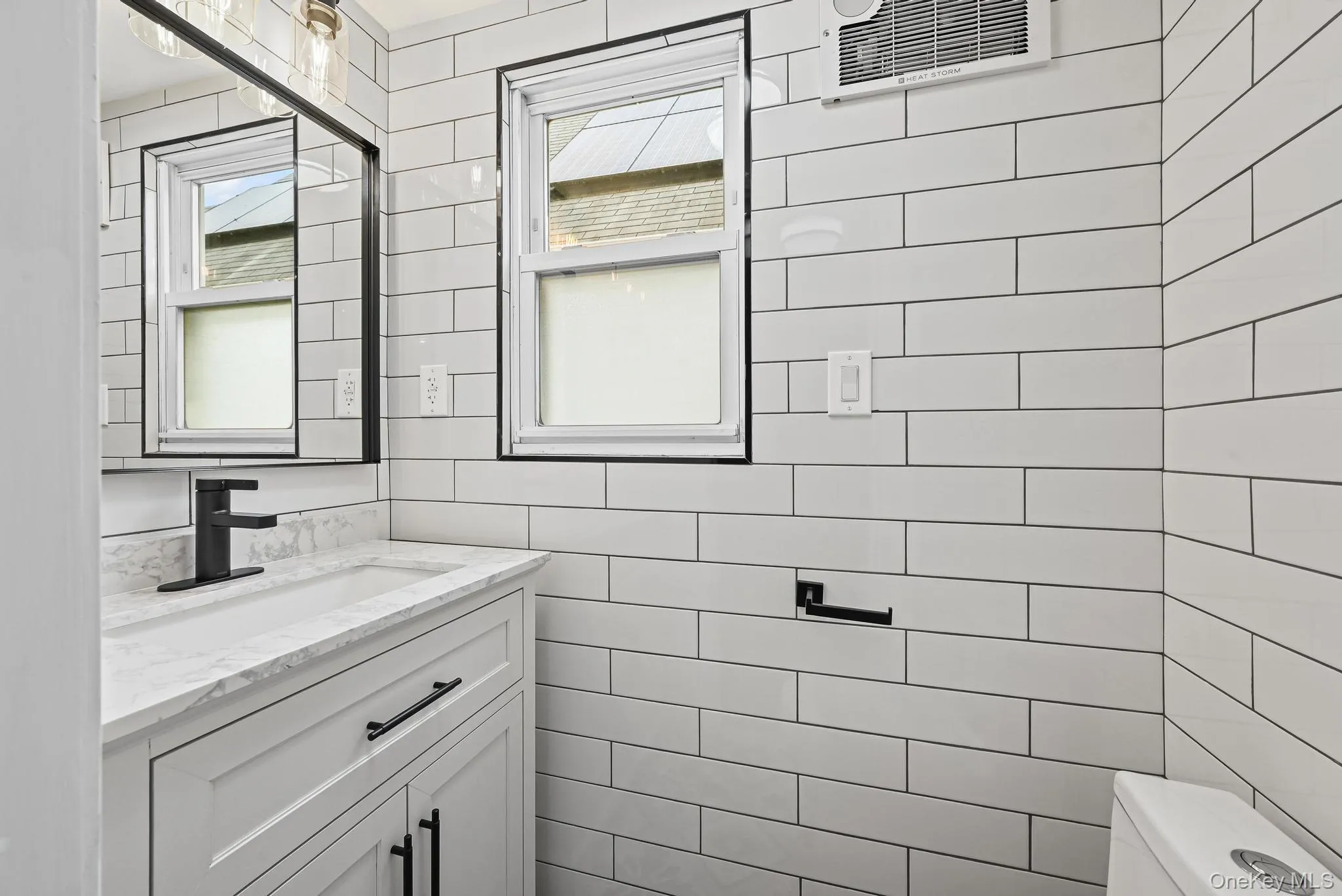 Bathroom featuring healthy amount of natural light, vanity, and tile walls Bathroom featuring healthy amount of natural light, vanity, and tile walls