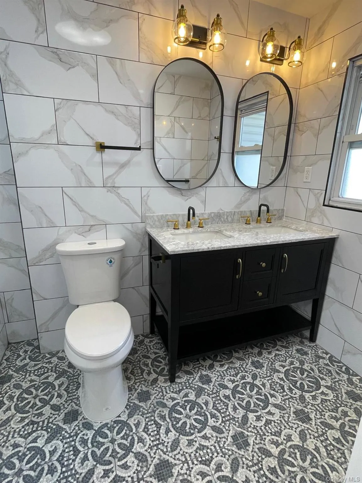Bathroom with tile walls, double vanity, and light tile patterned floors Bathroom with tile walls, double vanity, and light tile patterned floors