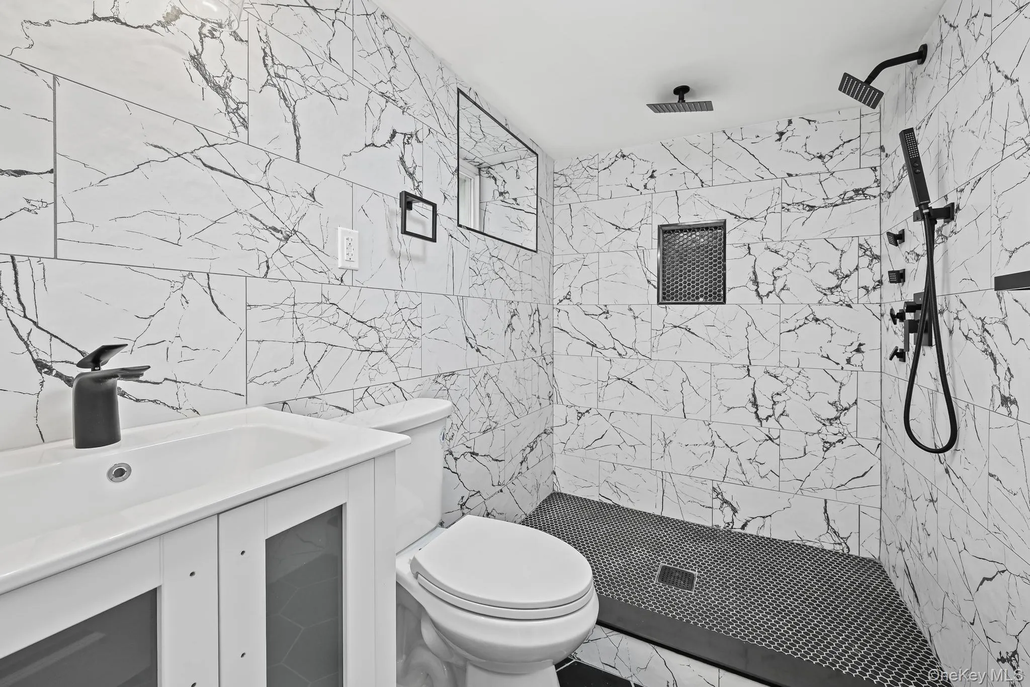 Full bathroom with tile walls, a marble finish shower, and vanity Full bathroom with tile walls, a marble finish shower, and vanity
