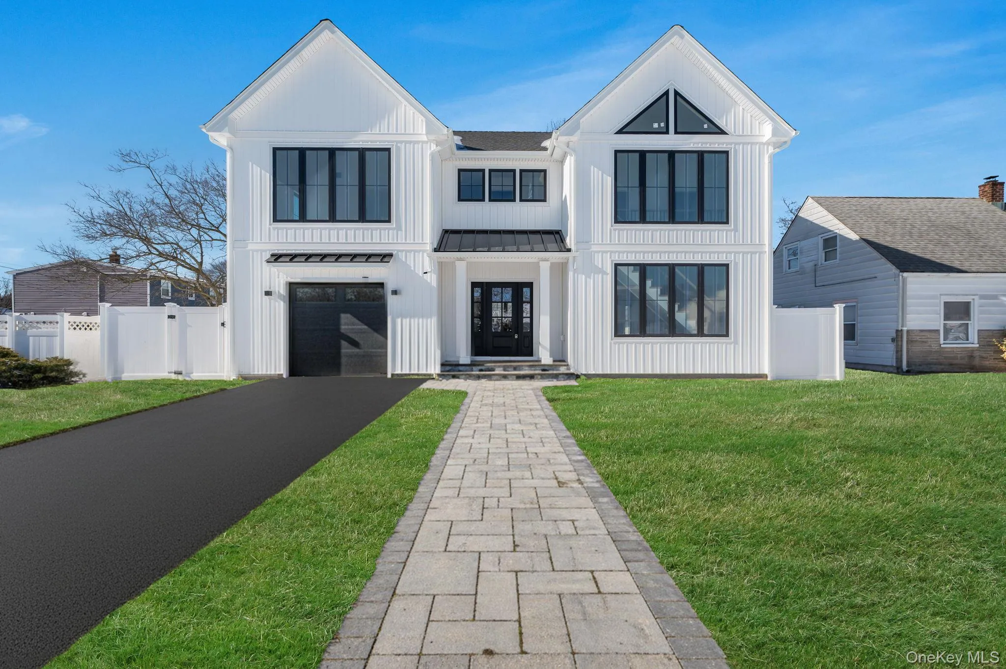 Modern Colonial exterior with board and batten style siding, black framed windows, and a covered entry that creates a strong, custom curb appeal. Modern Colonial exterior with board and batten style siding, black framed windows, and a covered entry that creates a strong, custom curb appeal.