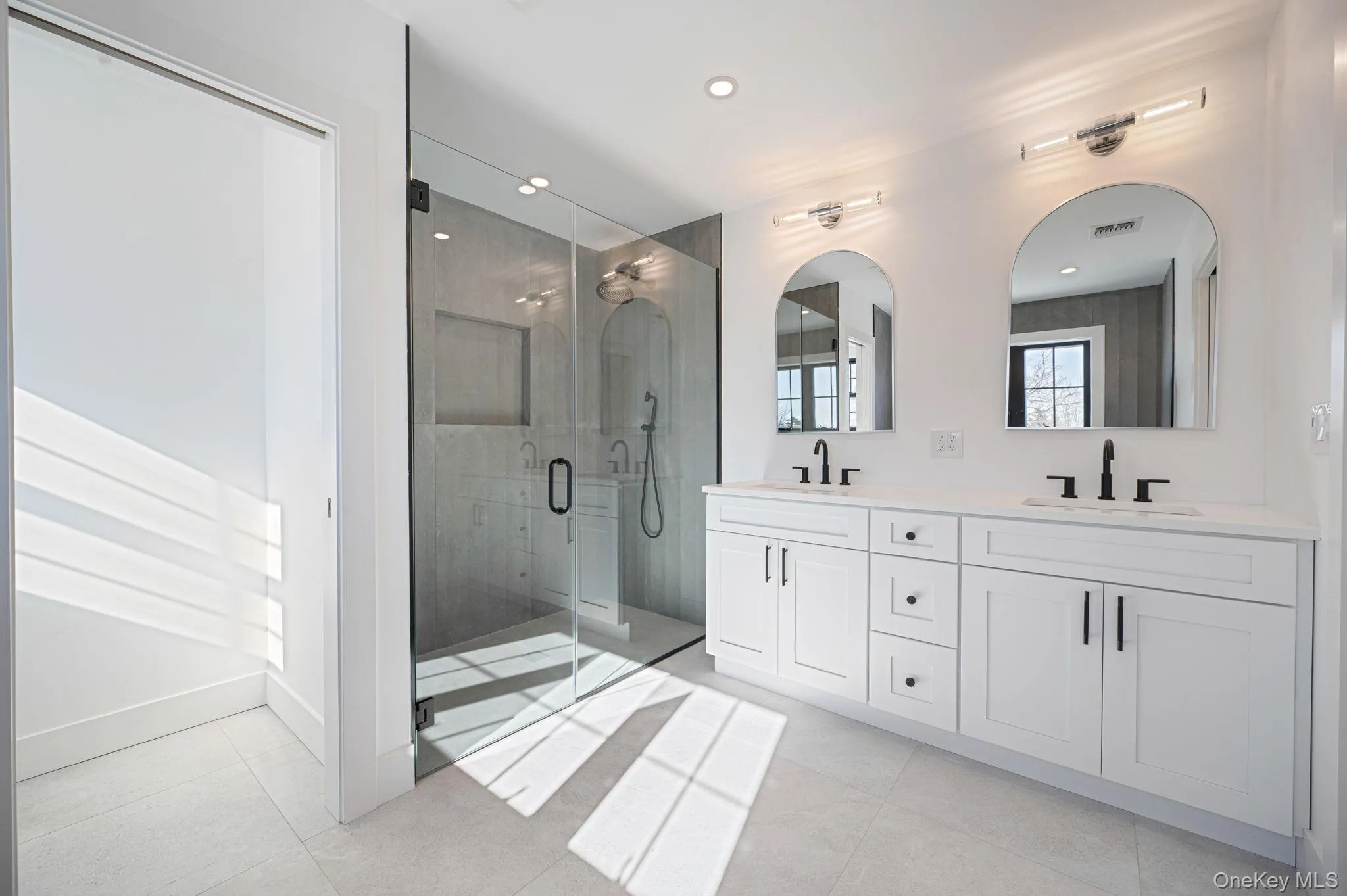 Spa like primary bath featuring a freestanding soaking tub, oversized glass shower, and modern finishes. Spa like primary bath featuring a freestanding soaking tub, oversized glass shower, and modern finishes.