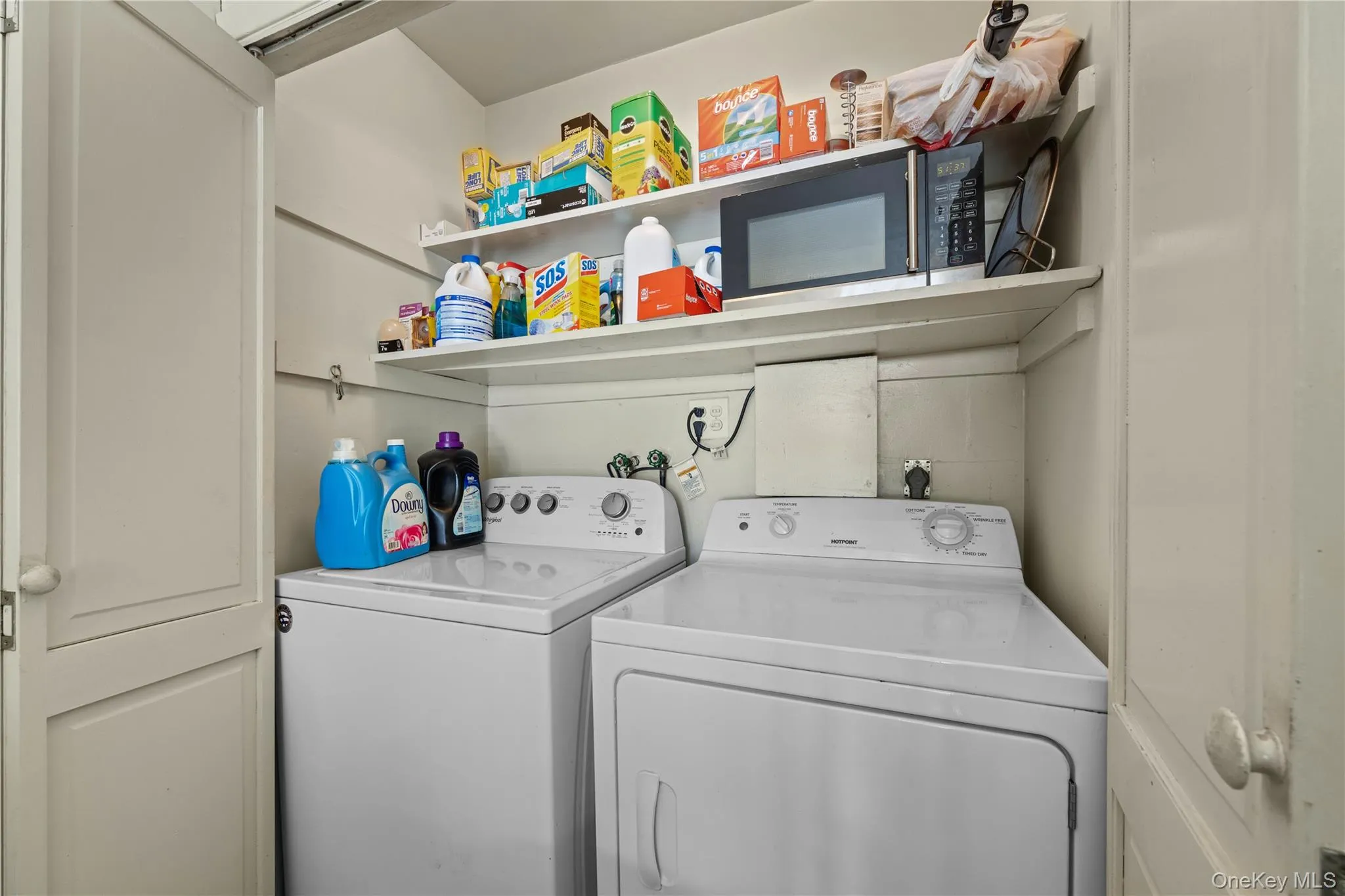 Dedicated laundry area featuring a white washing machine and dryer, built-in shelving, and white cabinetry Dedicated laundry area featuring a white washing machine and dryer, built-in shelving, and white cabinetry
