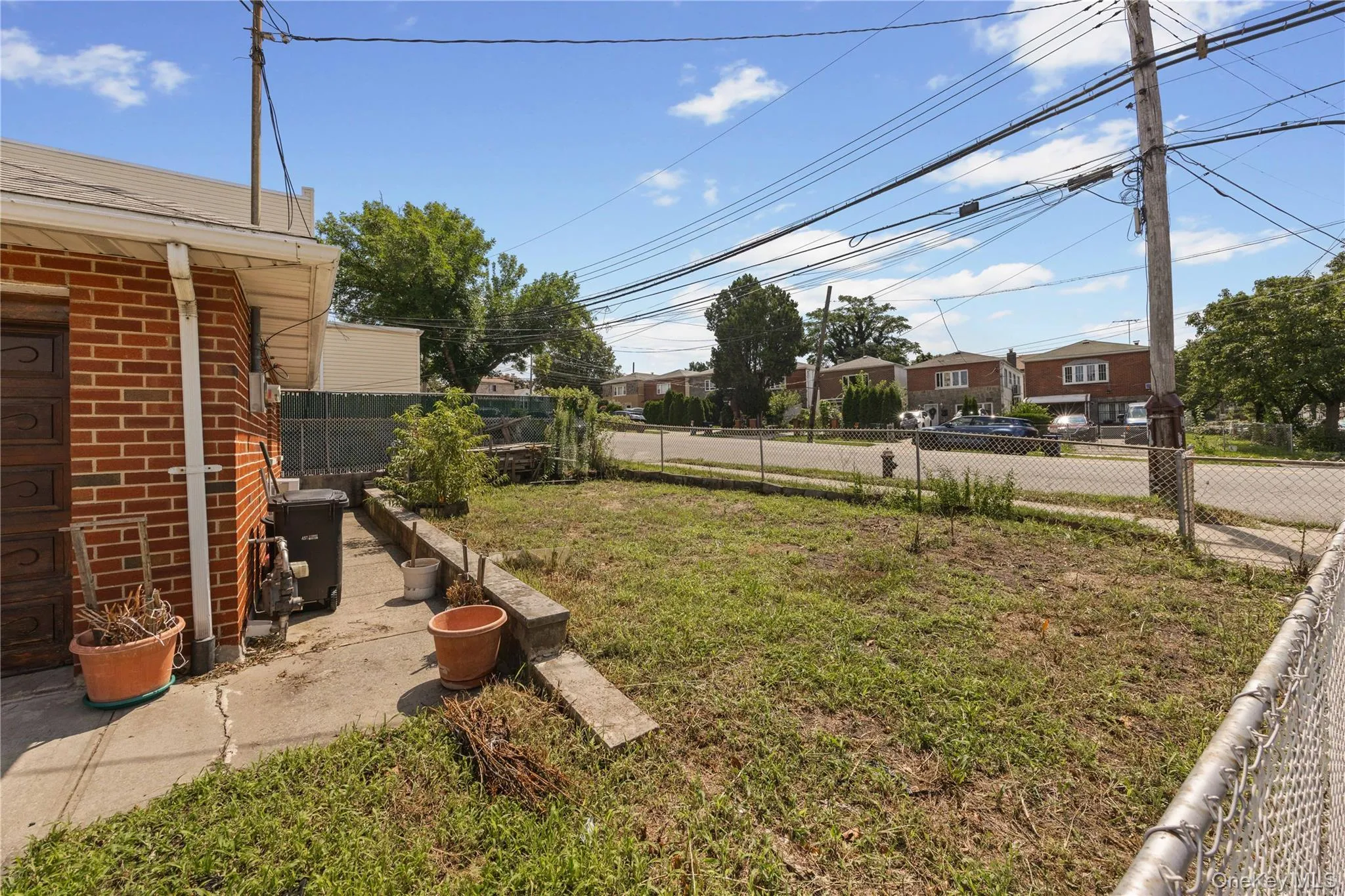 Rear yard with a concrete patio, retaining wall, and a chain-link fence bordering the property Rear yard with a concrete patio, retaining wall, and a chain-link fence bordering the property