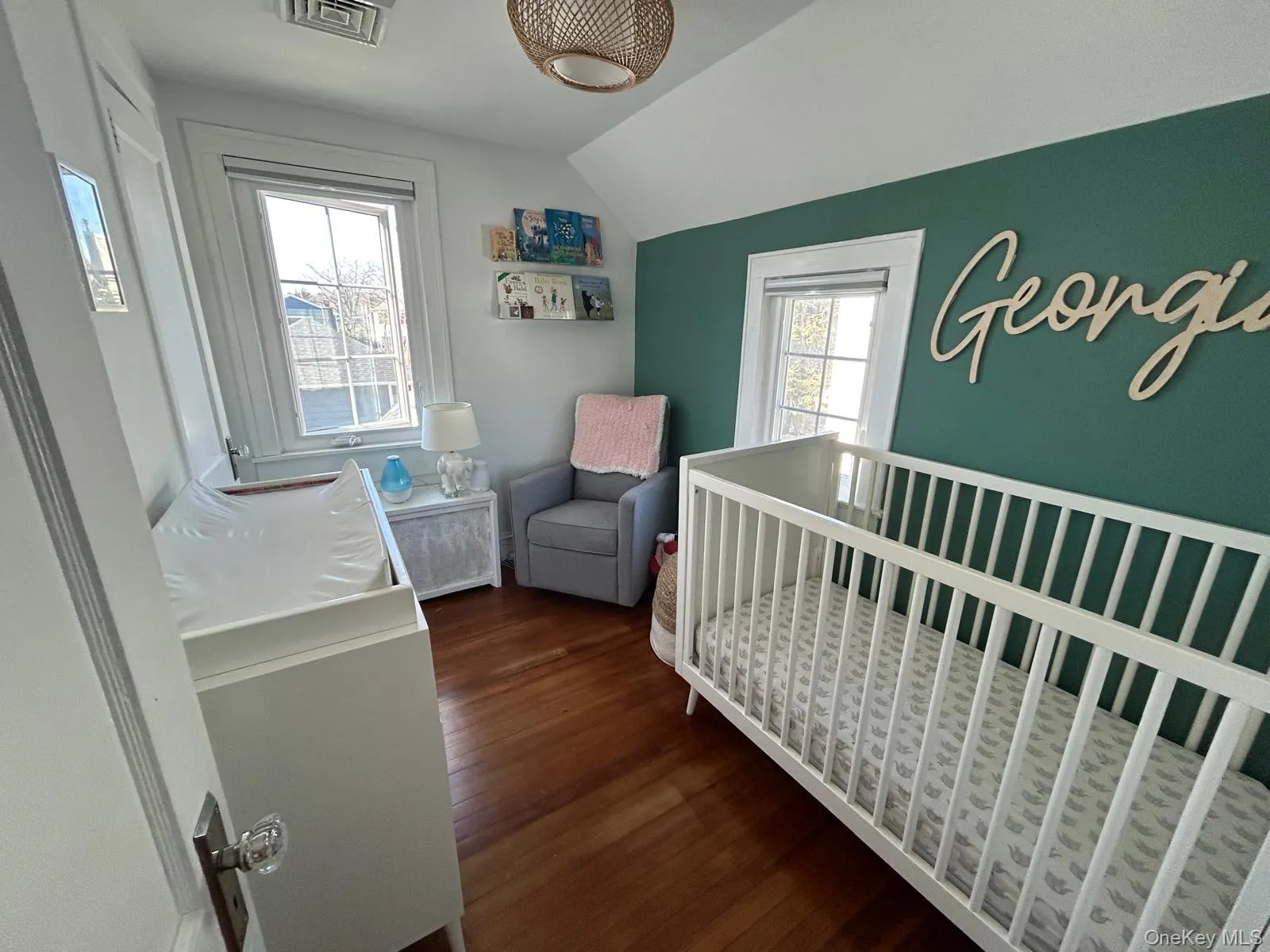 Bedroom with vaulted ceiling, dark wood-type flooring, a nursery area, and visible vents Bedroom with vaulted ceiling, dark wood-type flooring, a nursery area, and visible vents