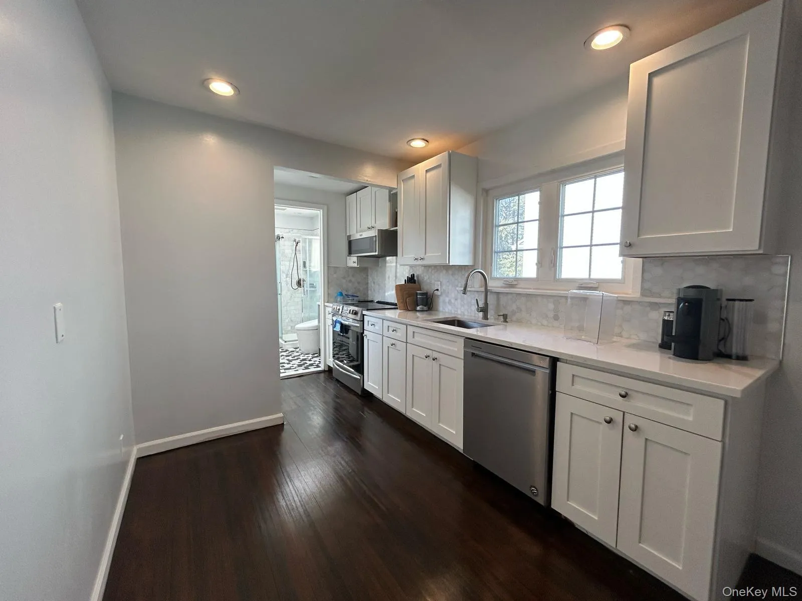 Kitchen featuring white cabinets, a sink, stainless steel appliances, and light countertops Kitchen featuring white cabinets, a sink, stainless steel appliances, and light countertops