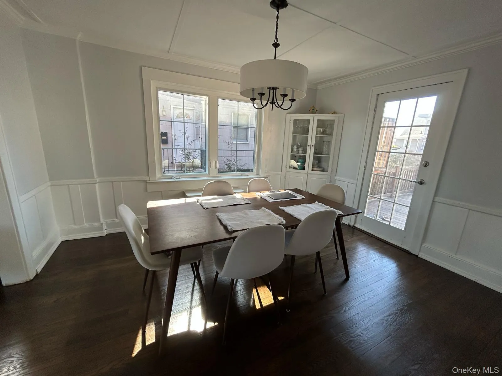 Dining space with dark wood-style floors, a decorative wall, crown molding, and wainscoting Dining space with dark wood-style floors, a decorative wall, crown molding, and wainscoting