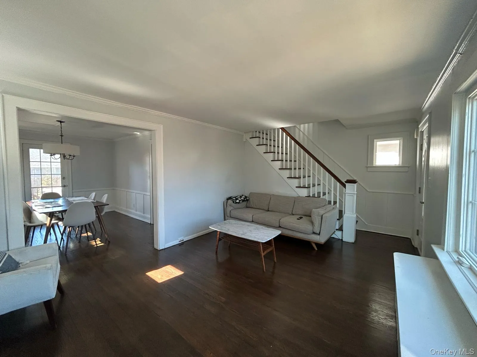 Living area with stairs, dark wood-type flooring, an inviting chandelier, and crown molding Living area with stairs, dark wood-type flooring, an inviting chandelier, and crown molding