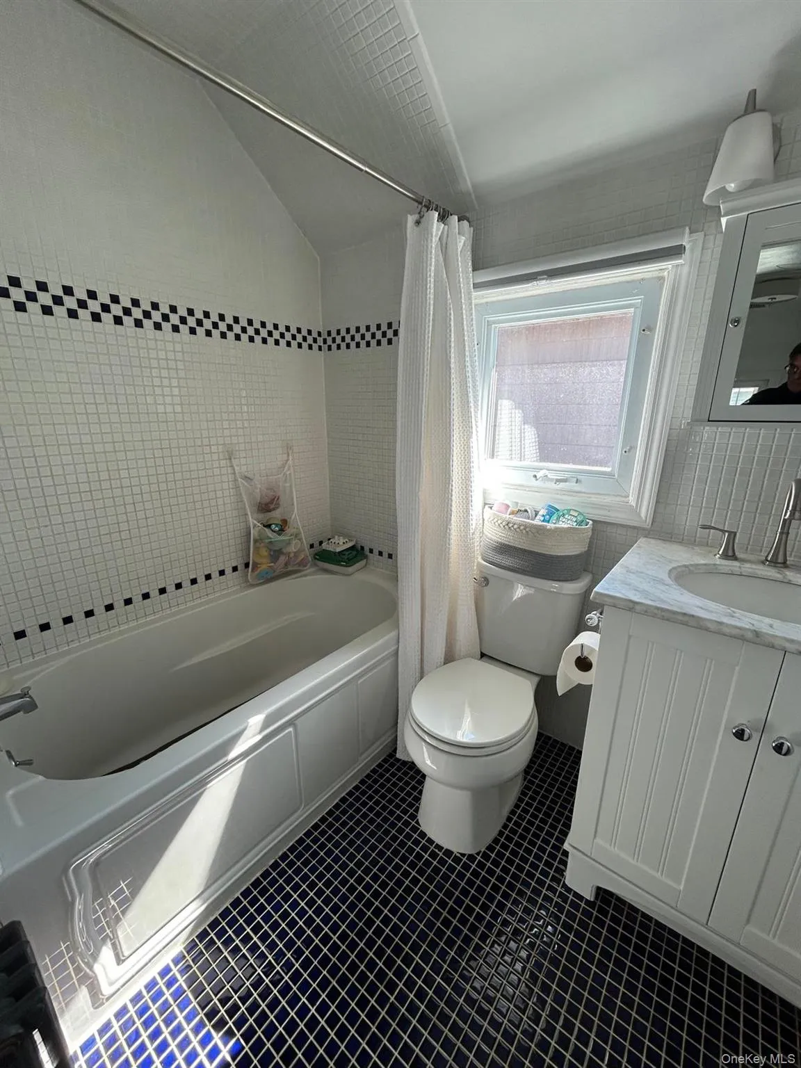 Full bath with toilet, shower / bath combo, vaulted ceiling, vanity, and tile patterned flooring Full bath with toilet, shower / bath combo, vaulted ceiling, vanity, and tile patterned flooring