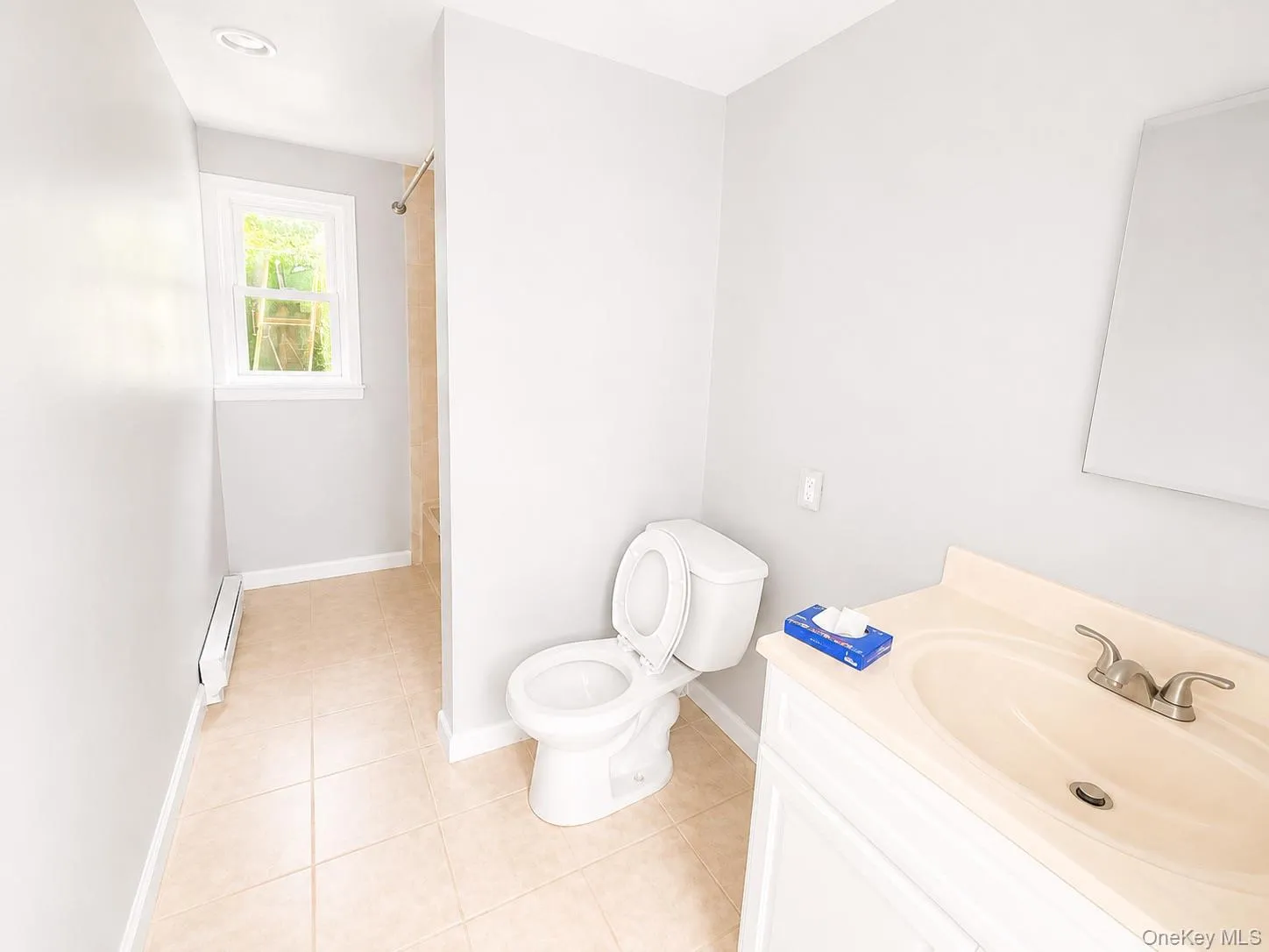 Tile flooring, single vanity with integrated sink, and white toilet Tile flooring, single vanity with integrated sink, and white toilet