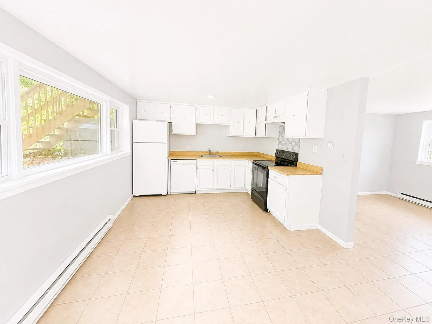 Kitchen featuring white cabinetry, light wood-finish countertops, and a tile backsplash Kitchen featuring white cabinetry, light wood-finish countertops, and a tile backsplash