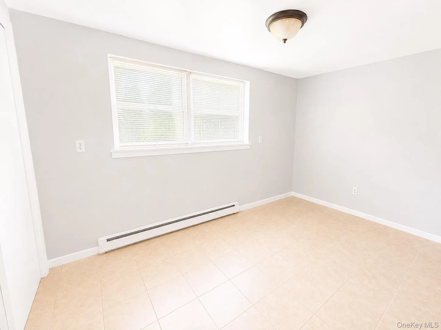 Tile flooring, light gray wall paint, white trim, window with blinds, flush mount ceiling light fixture Tile flooring, light gray wall paint, white trim, window with blinds, flush mount ceiling light fixture