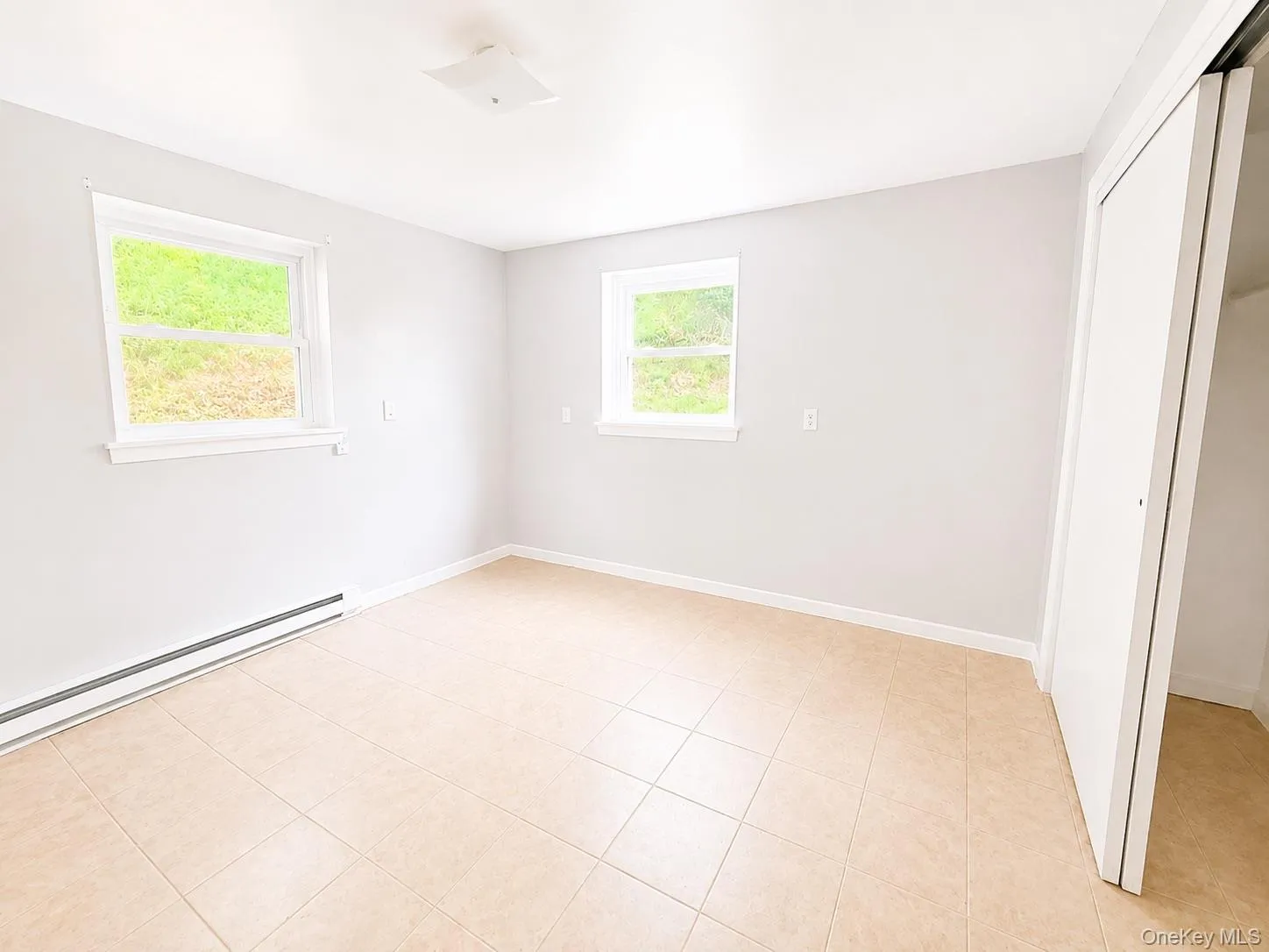Neutral-toned tiled flooring, white walls, and two windows with white trim Neutral-toned tiled flooring, white walls, and two windows with white trim