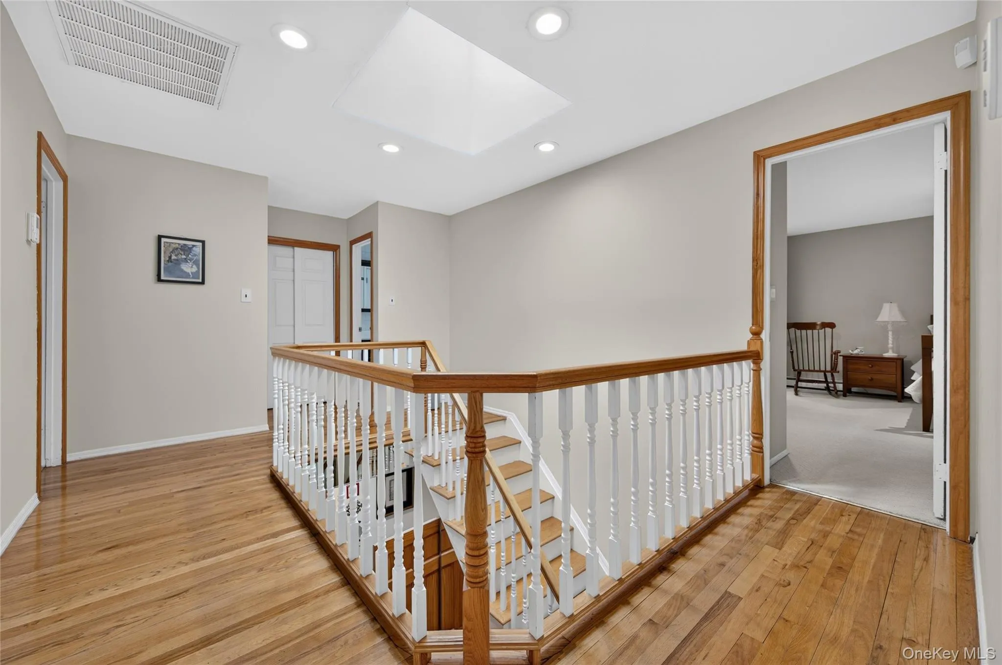 Hardwood flooring, recessed lighting, skylight, wood banister with white spindles Hardwood flooring, recessed lighting, skylight, wood banister with white spindles