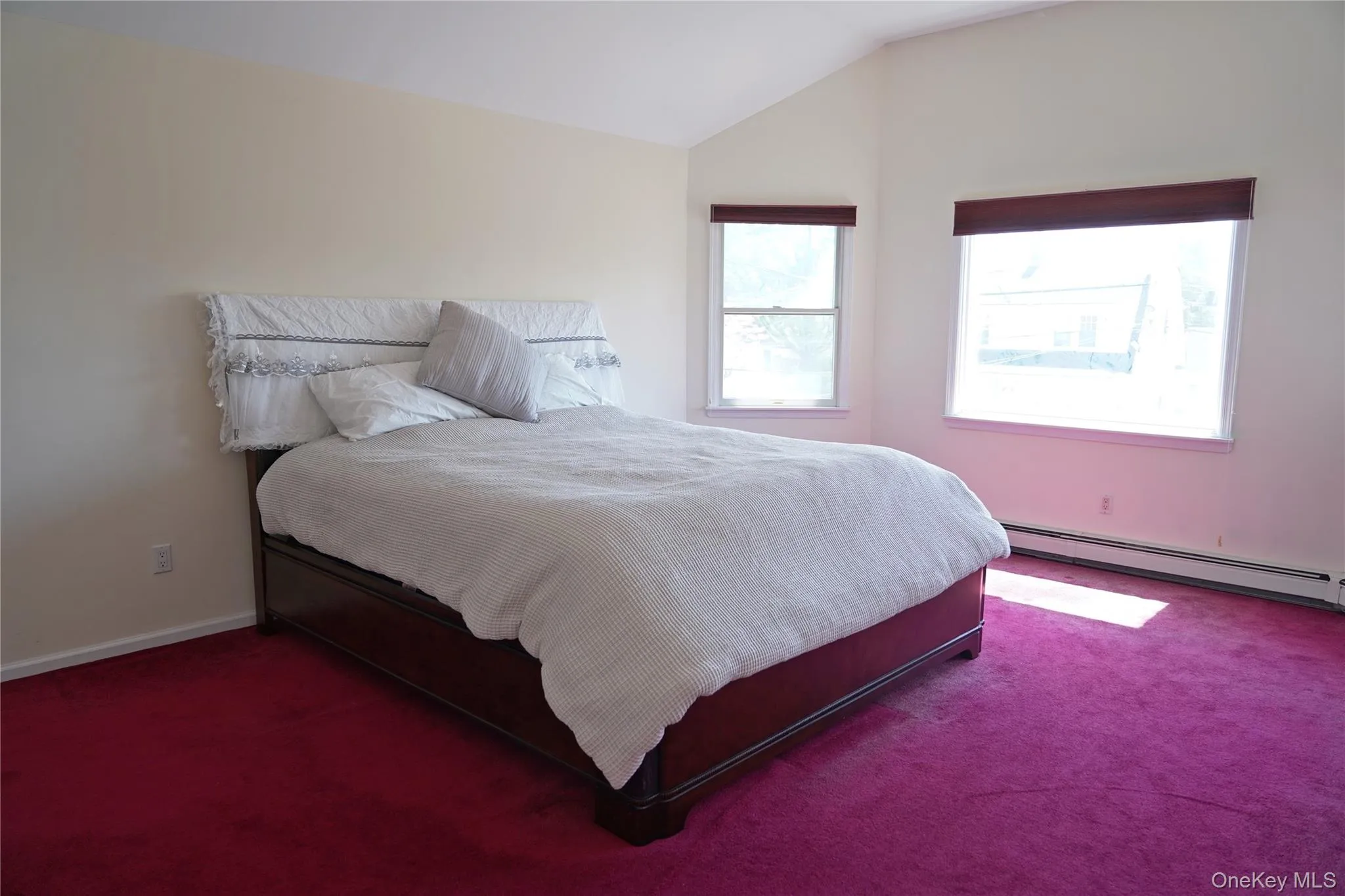 Bedroom with a baseboard heating unit, vaulted ceiling, carpet, and baseboards Bedroom with a baseboard heating unit, vaulted ceiling, carpet, and baseboards