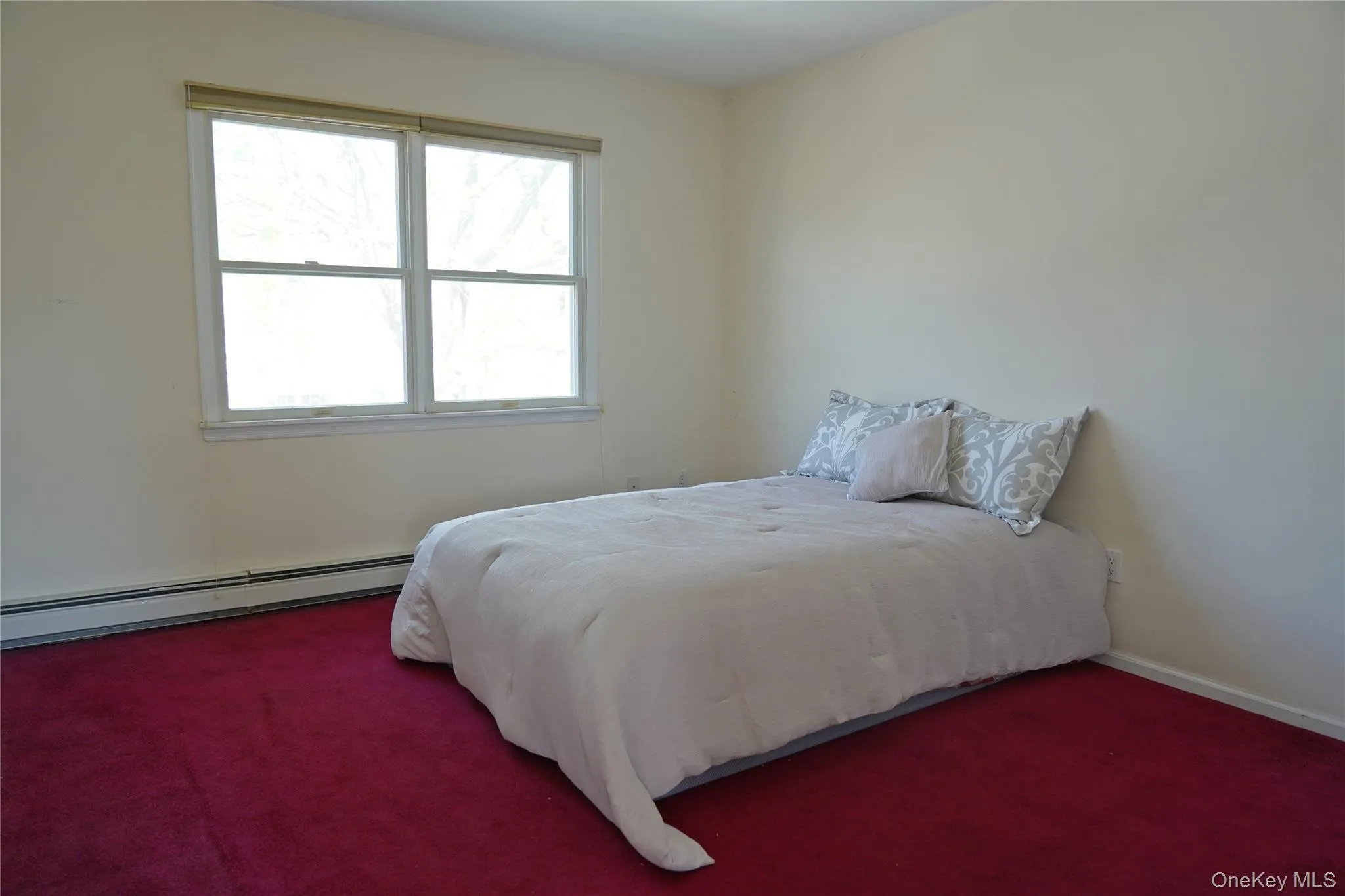 Carpeted bedroom with baseboards, baseboard heating, and multiple windows Carpeted bedroom with baseboards, baseboard heating, and multiple windows