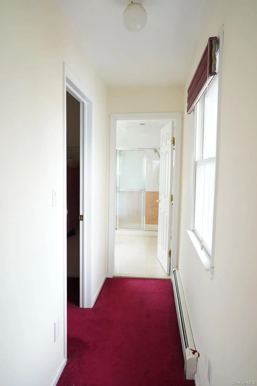 Corridor featuring carpet, a baseboard heating unit, and baseboards Corridor featuring carpet, a baseboard heating unit, and baseboards