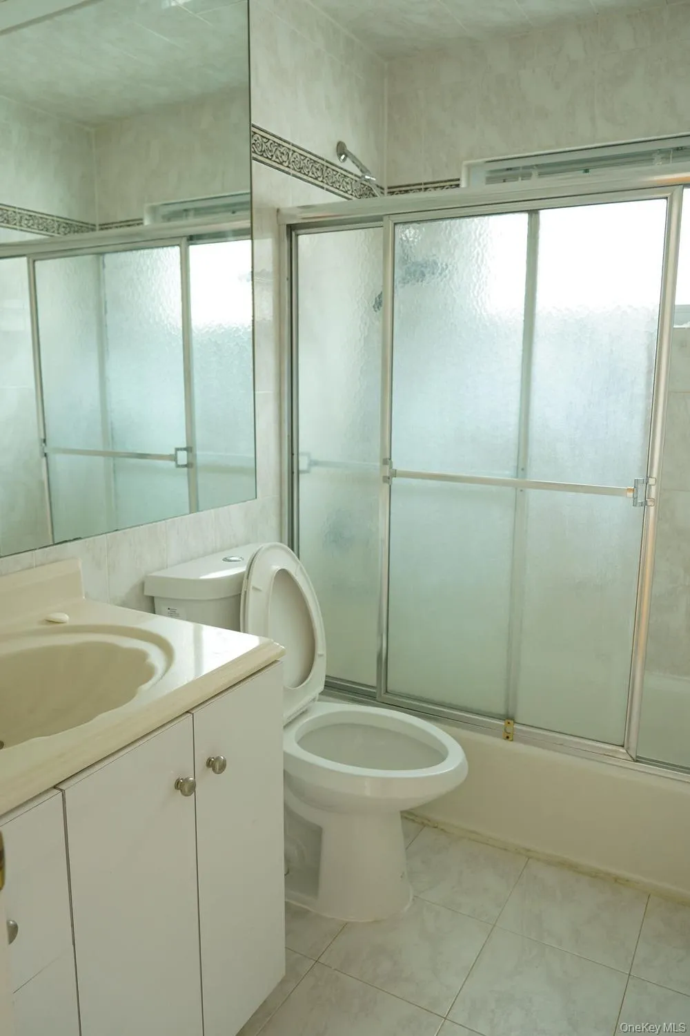 Full bath featuring toilet, enclosed tub / shower combo, and vanity Full bath featuring toilet, enclosed tub / shower combo, and vanity